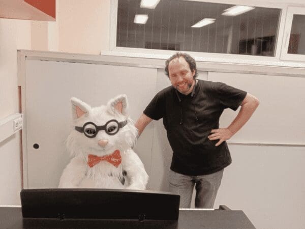 Custom look-alike cat plush in round glasses and a red bow tie, made to order as a gift for the man beside it