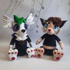 Two custom furry plushies side by side: a white OC with purple markings and a cream cat fursona