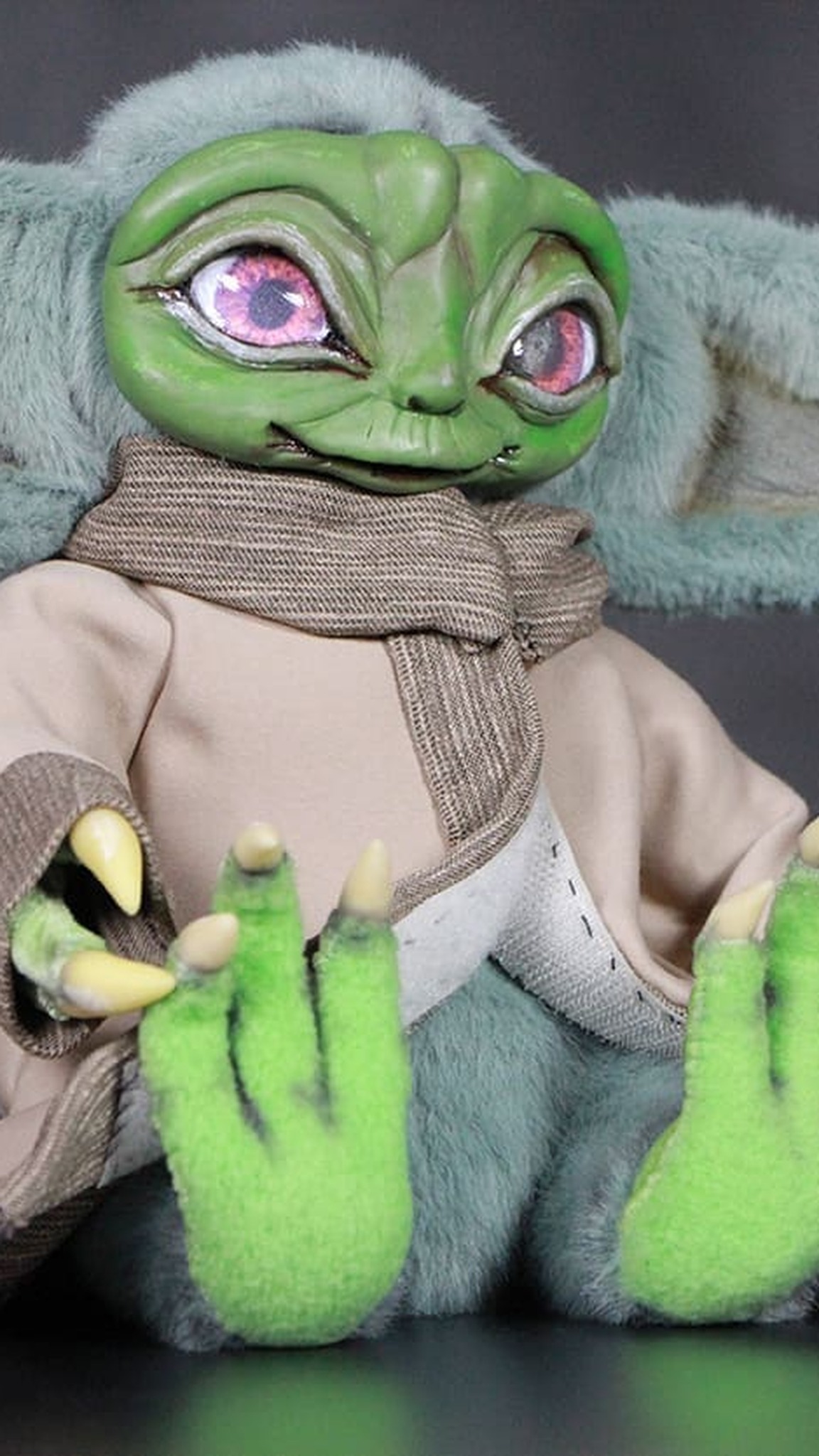 Handmade Baby Yoda doll sitting with his green clawed hands up, a custom Grogu doll with a frame inside