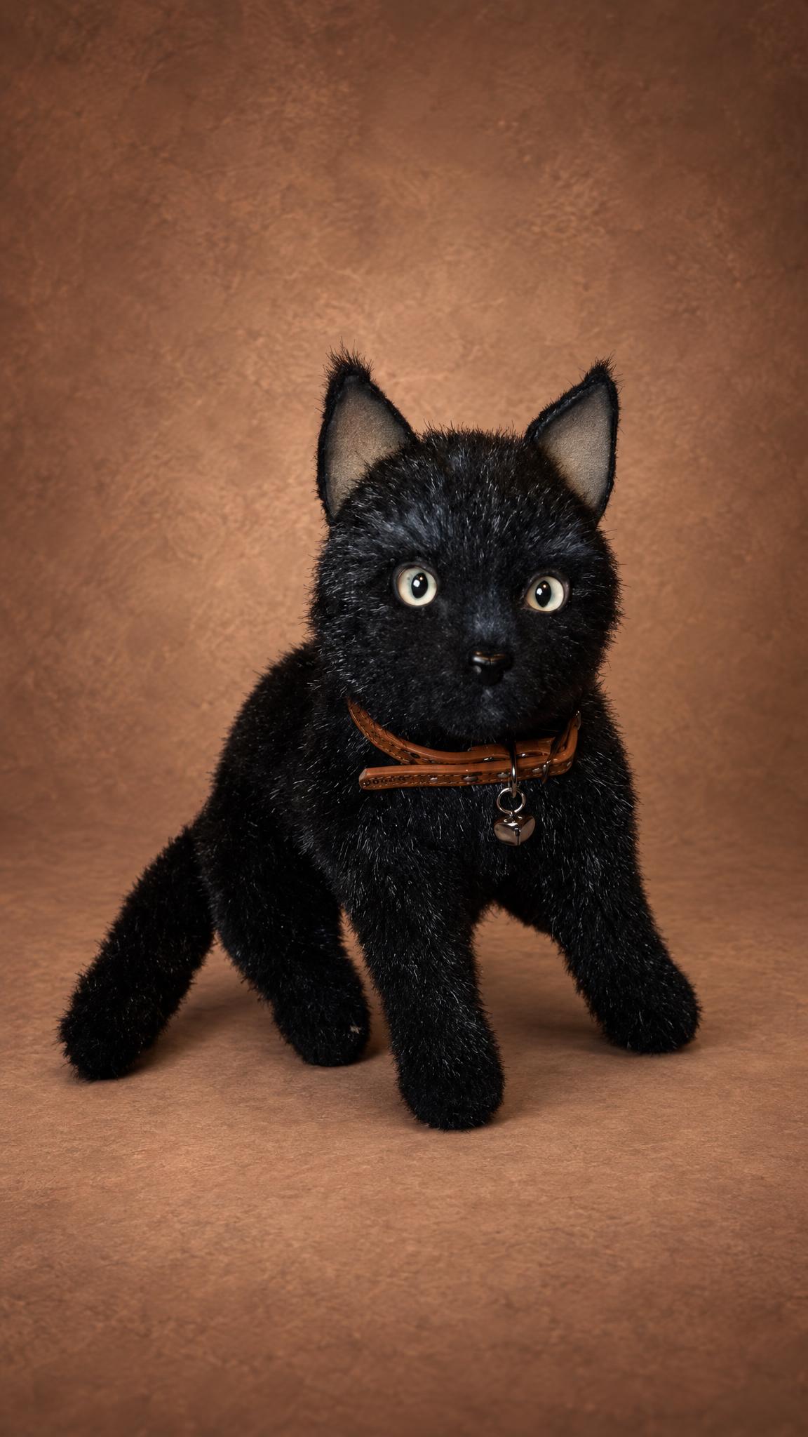 Realistic black cat plush sitting up, green eyes and a bell on its collar, handmade to order
