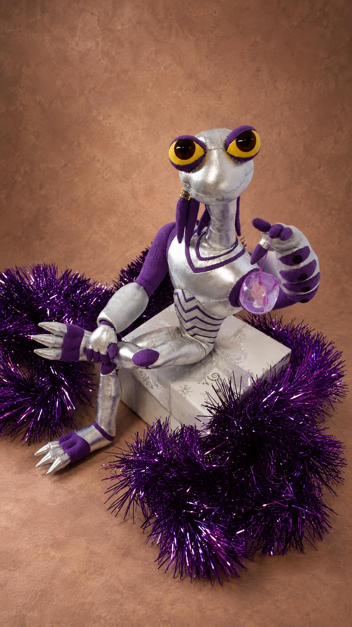 Croakagy frog alien plush lounging in purple tinsel, silver claws and yellow eyes, handmade Space Dogs toy