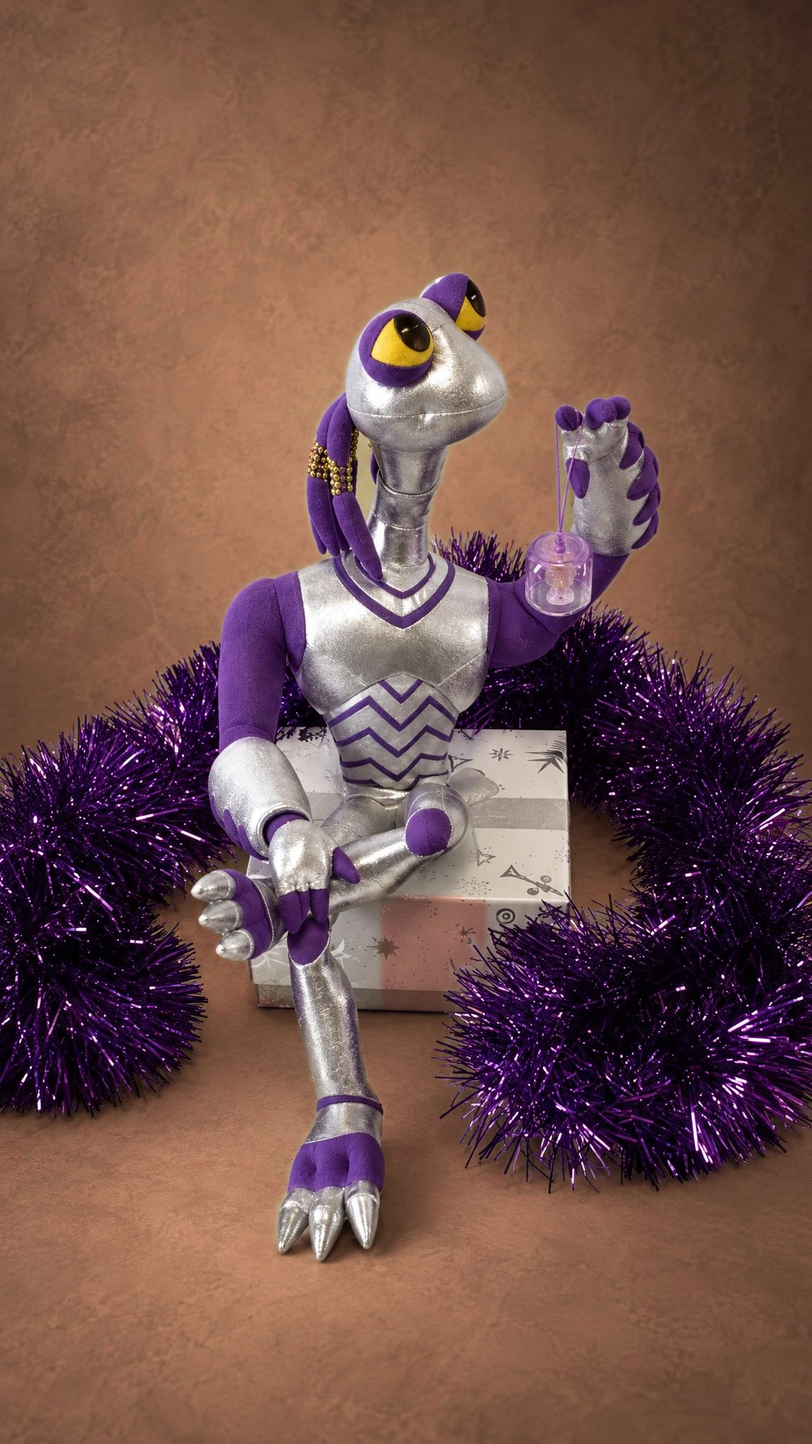 Custom Croakagy plush from Space Dogs holding a small purple cup, sitting among purple tinsel, made to order