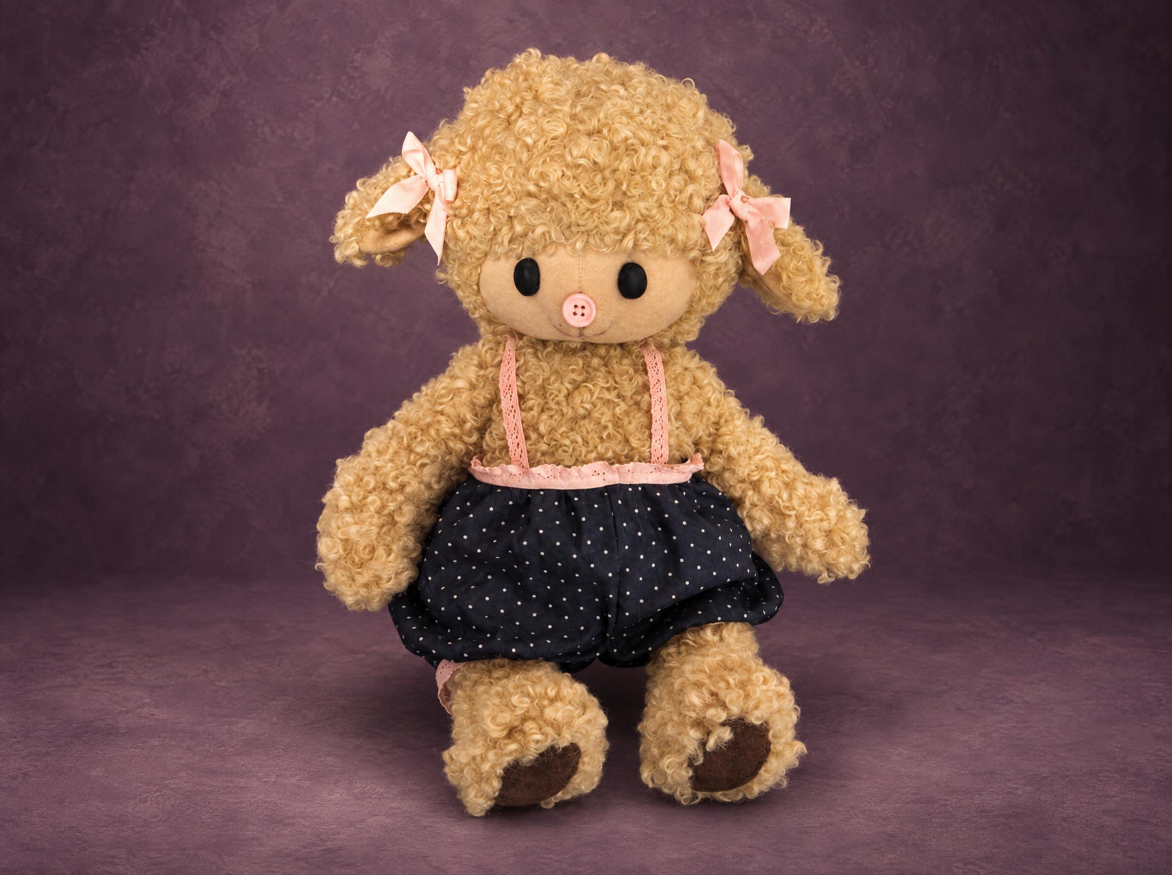Curly sheep plush in a polka-dot skirt Curly sheep plush in a navy polka-dot skirt with pink lace braces, a handmade prototype for a toy brand