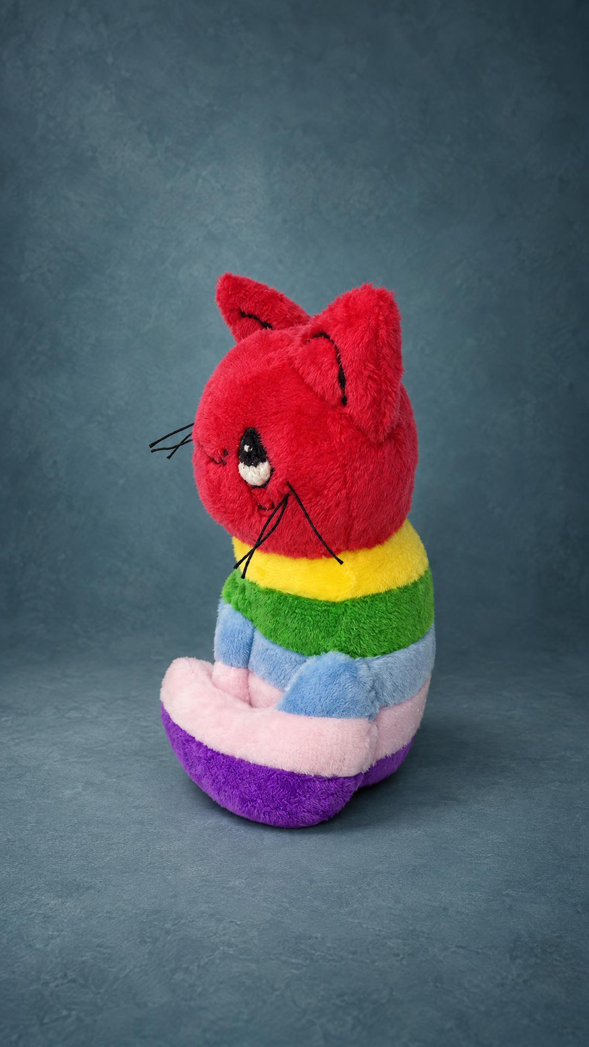 Handmade rainbow cat plush sewn to order from a child's drawing, pink tail curled round its striped body