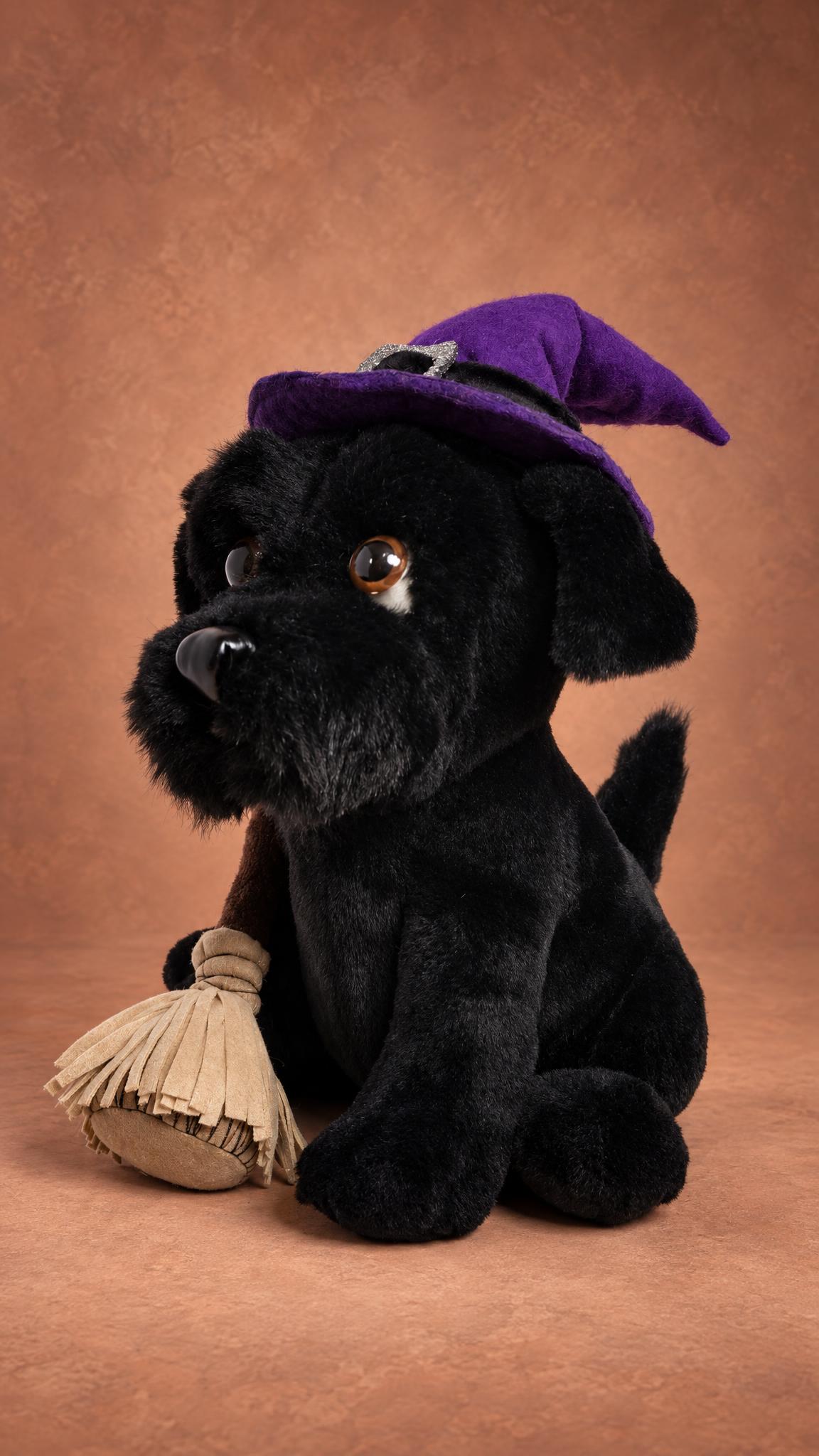 Custom dog mascot plush: black terrier with a shaggy muzzle, bent purple hat tip and a beige broom, sewn by hand