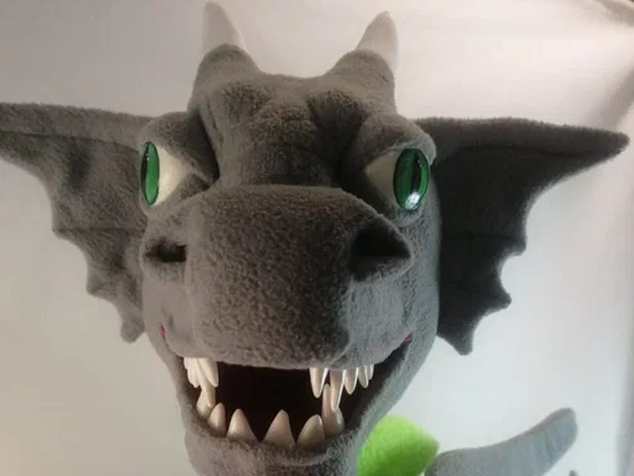 Custom dragon mascot plush with an open grin Custom dragon mascot plush with a wide open grin, green slit eyes and white horns, gray fleece, made to order for a team