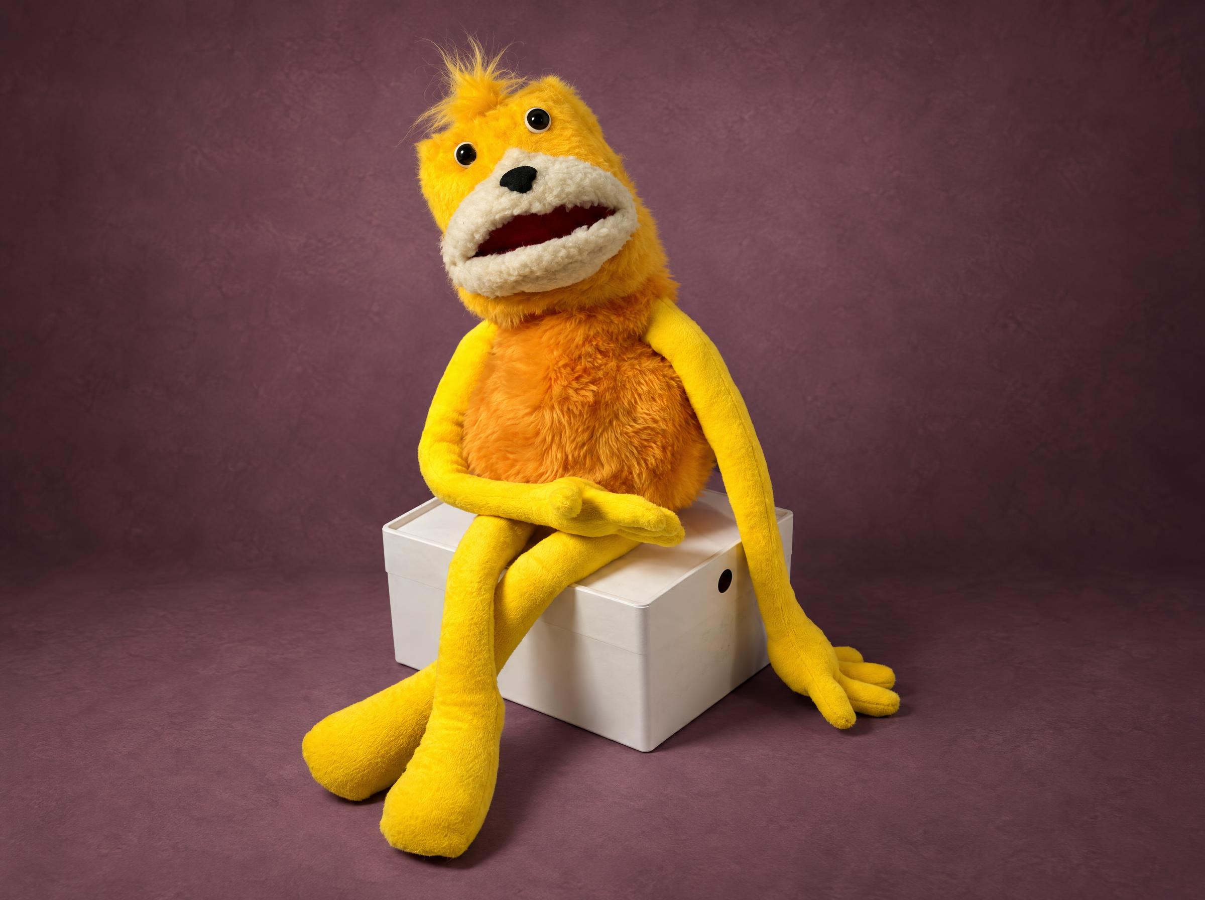 Custom Flat Eric Plush with Long Yellow Arms Custom Flat Eric plush sewn to order, mouth open, long yellow arms folded over his knees on a white box