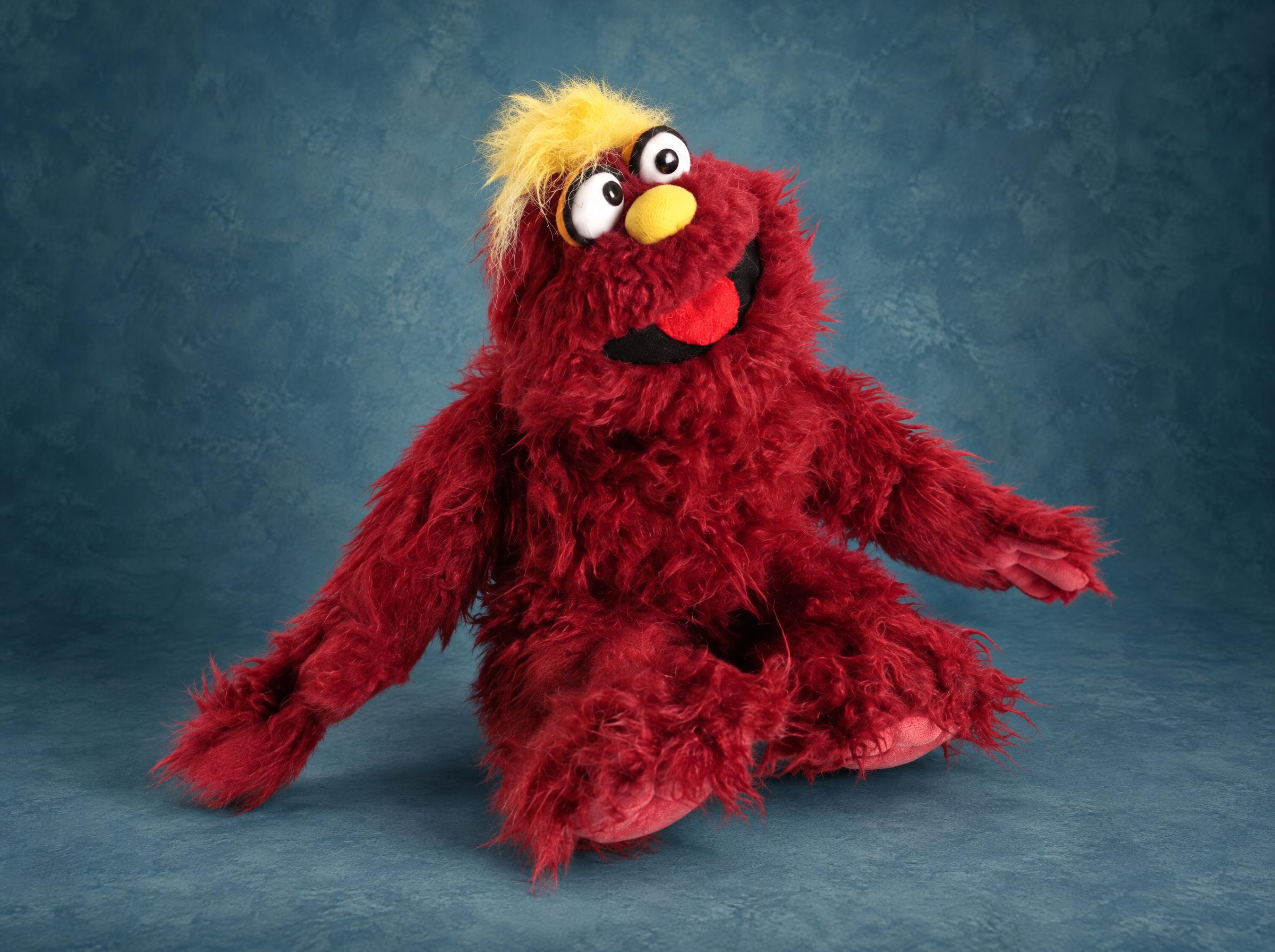 Custom Muppet-style monster puppet made to order, shaggy red fur, yellow hair tuft, big eyes and red tongue