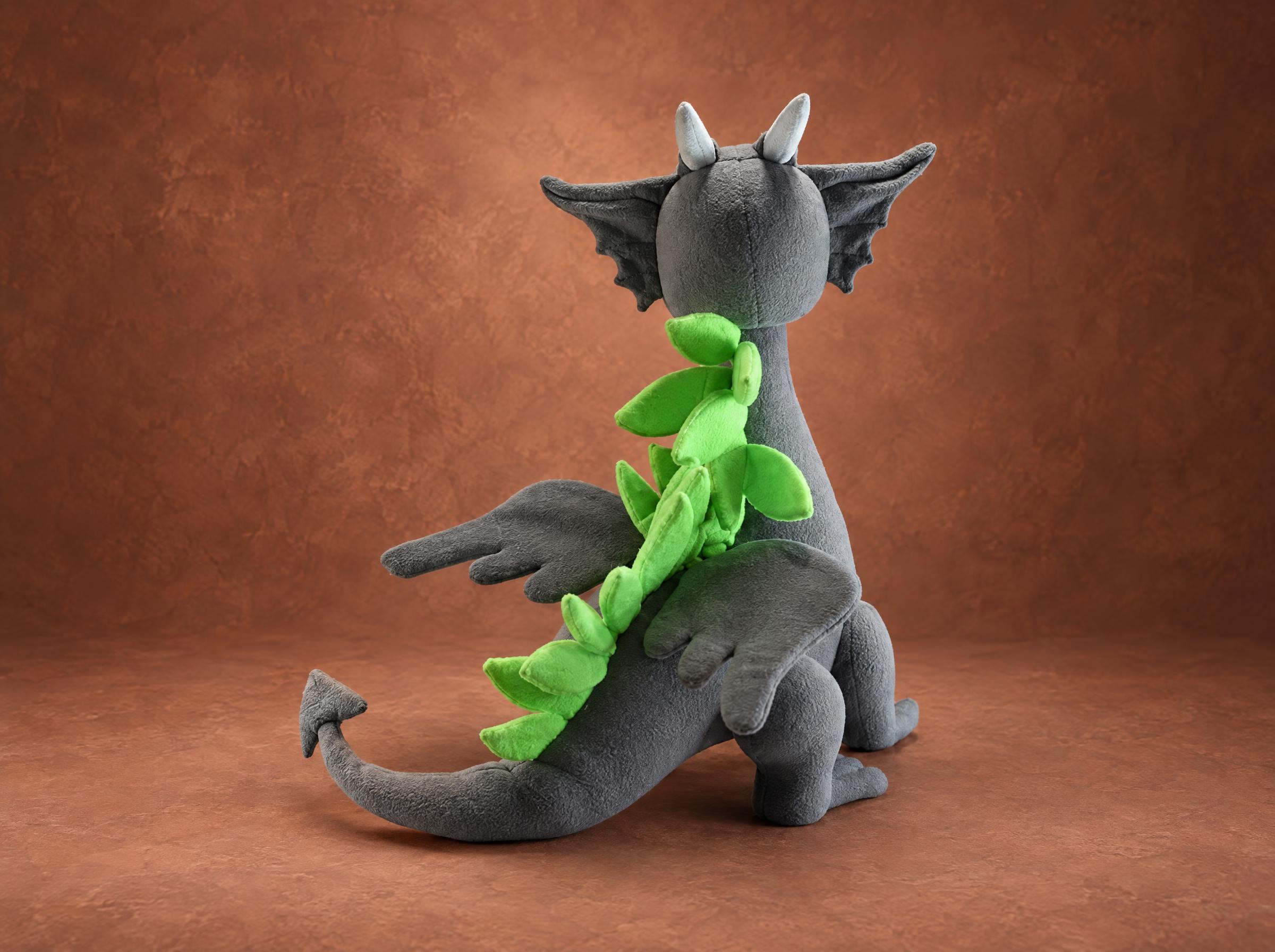 Dragon mascot plush with lime-green back spikes Dragon mascot plush from behind: a row of lime-green fleece spikes, gray bat wings and an arrow tail, handmade