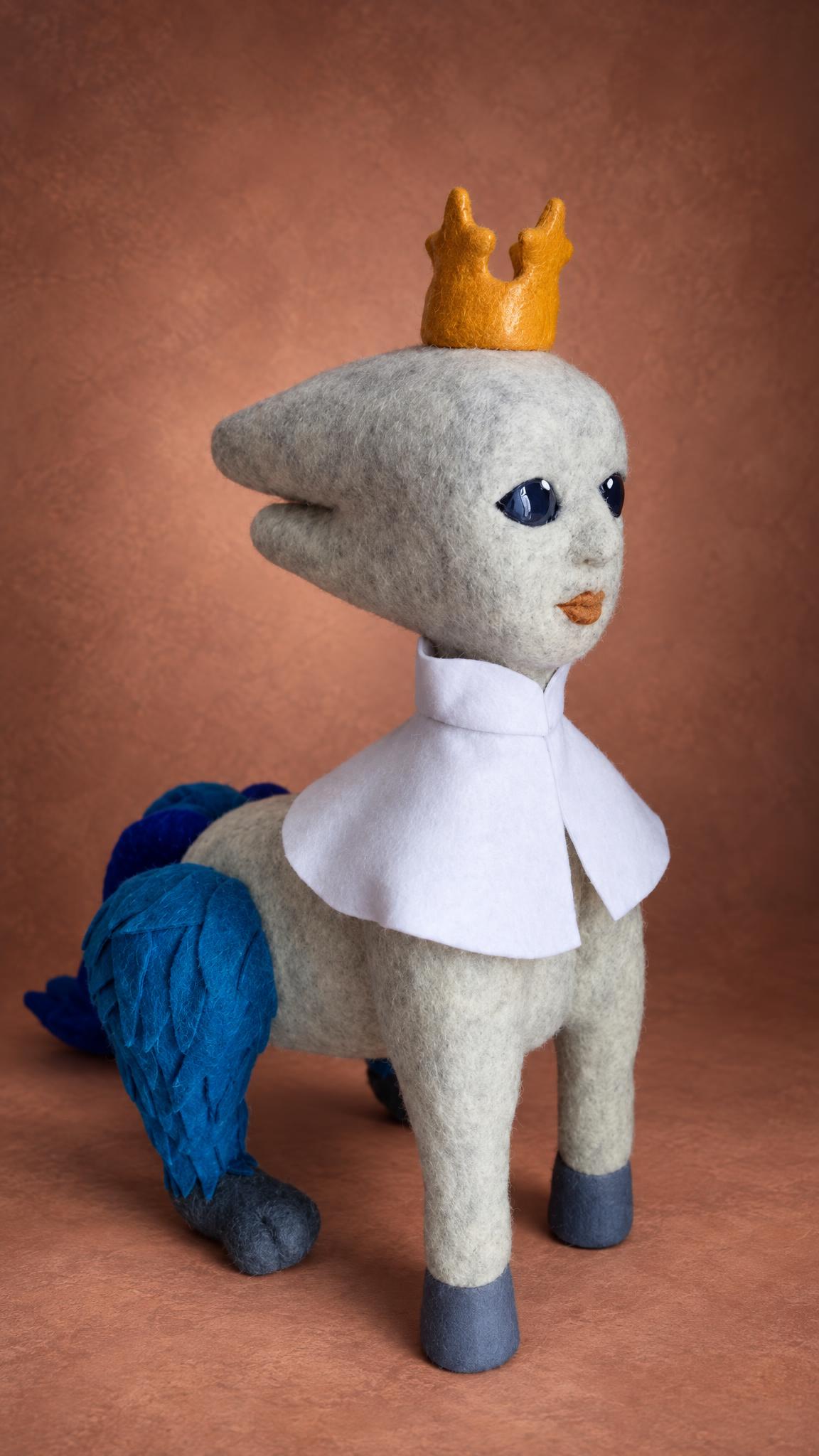 Handmade fantasy creature plush with a crown and blue felt tail, a custom toy felted to order from a painting
