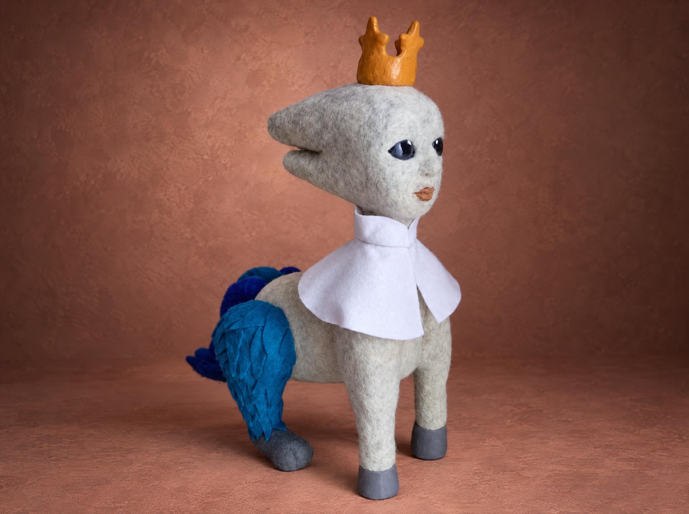 Fantasy creature plush with a crown and blue tail Custom fantasy creature plush turning its head, gold crown, white cape and blue felt tail, felted by hand to order from a painting