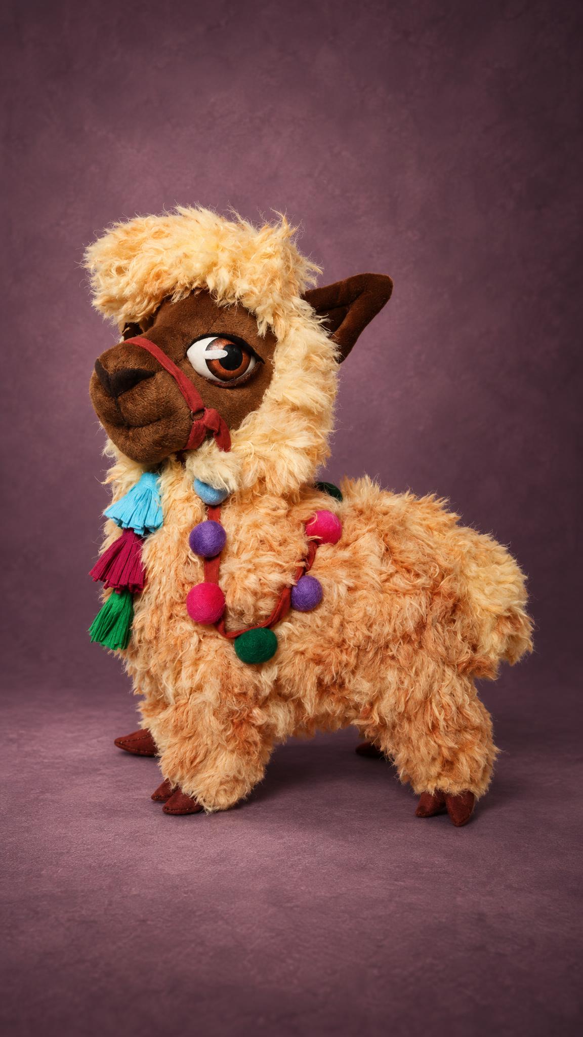 Handmade llama plush with big brown eyes, a red halter and colorful tassels, a custom stuffed llama