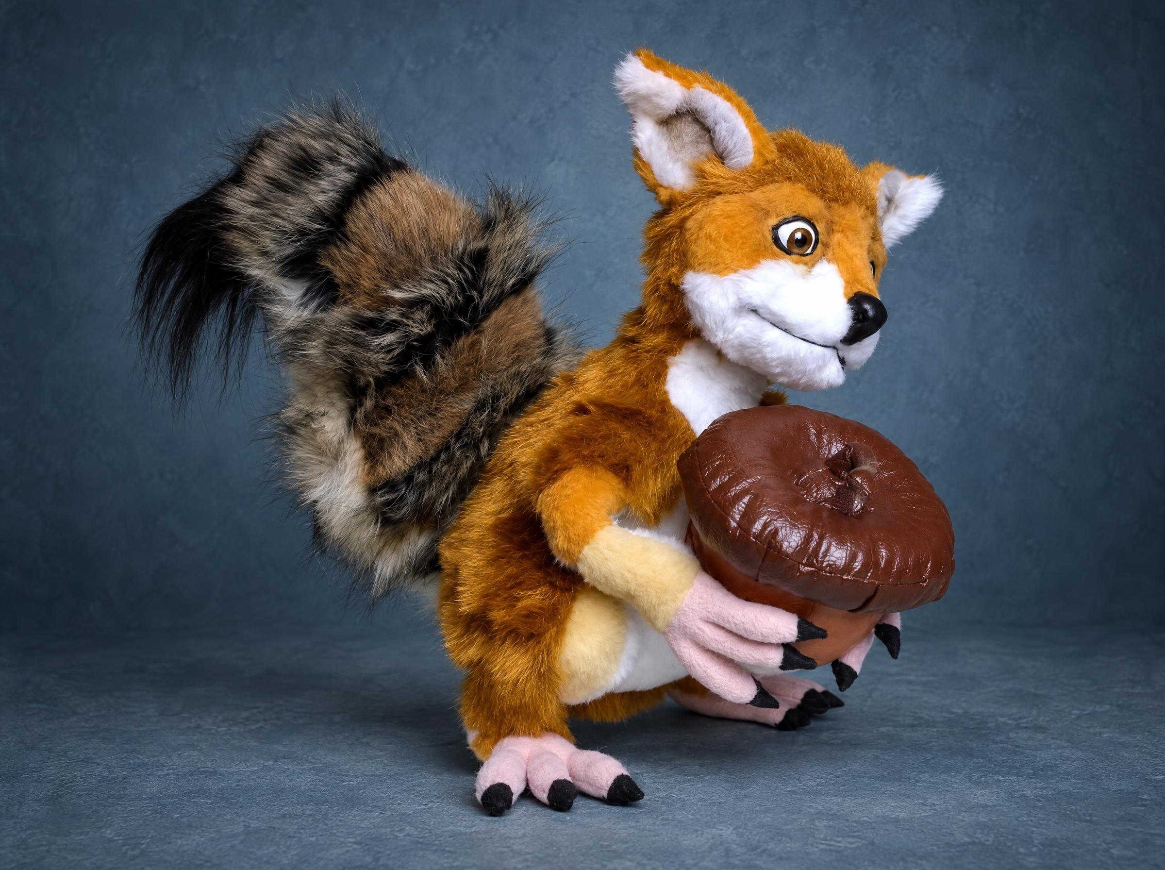 Foxsquirrel plush with a bushy squirrel tail Foxsquirrel plush from the side with a huge bushy grey-brown squirrel tail and an acorn, a custom meme toy made to order