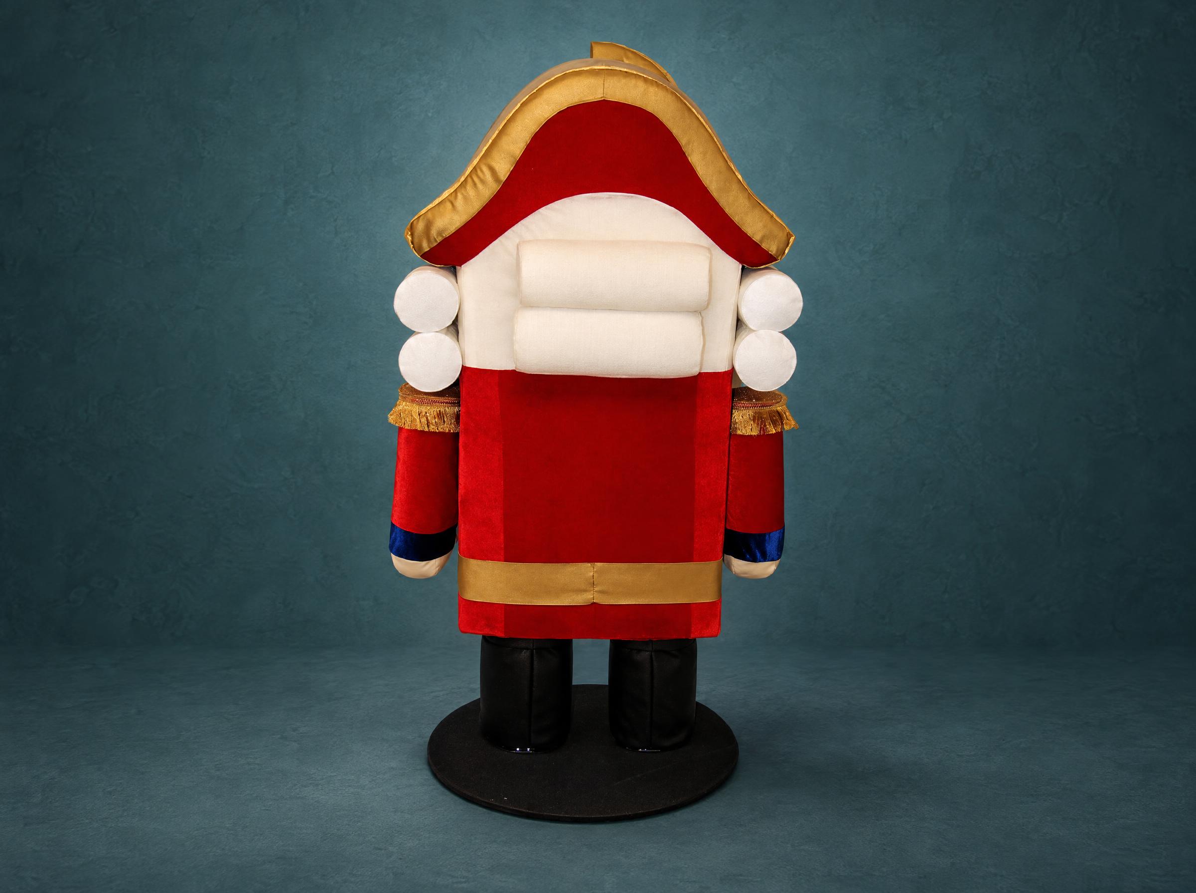 Giant Nutcracker plush with rolled wig curls Giant Nutcracker plush with white rolled wig curls under a gold-trimmed hat and a red velvet coat, made to order