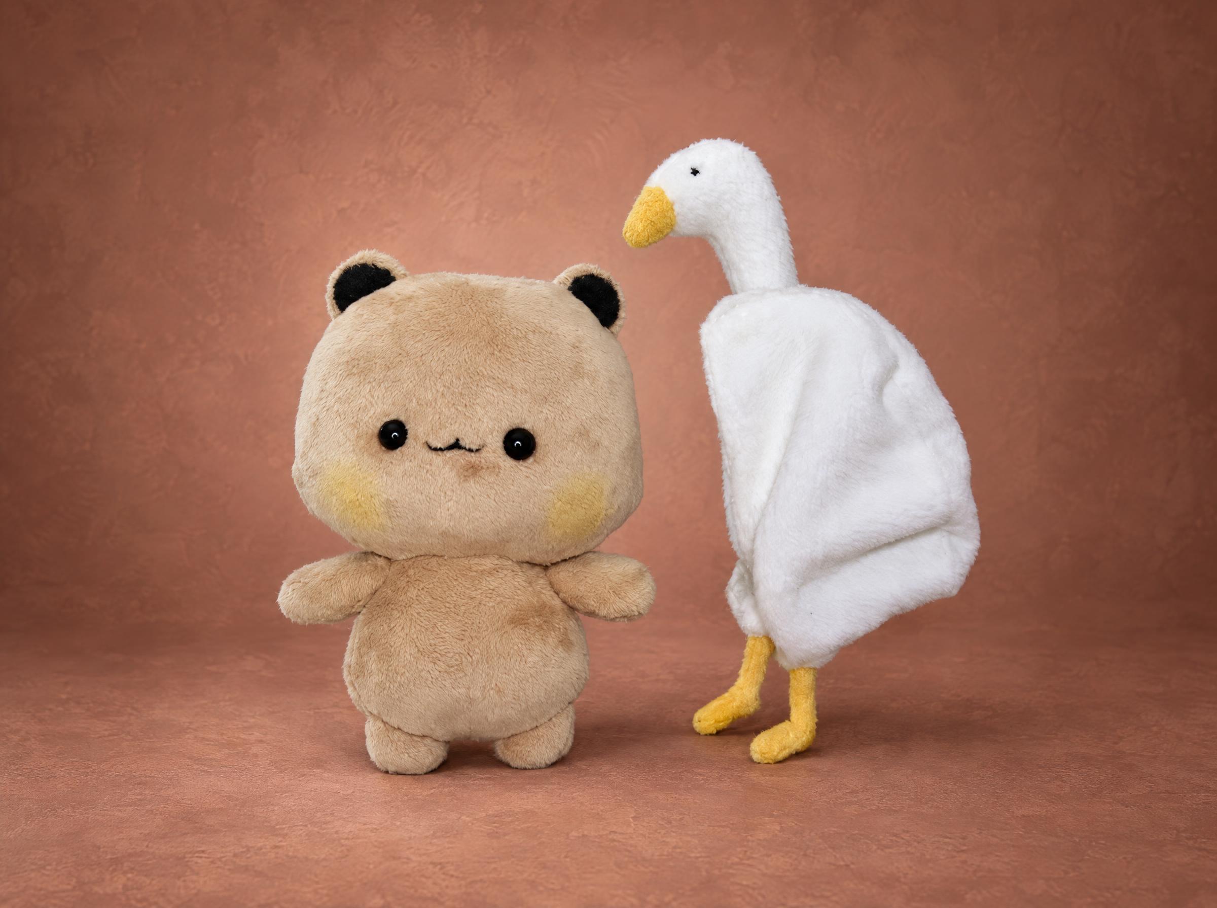 Goose hoodie bear plush with the hood off Beige bear plush standing next to its white goose hoodie, the removable costume of a custom sticker toy