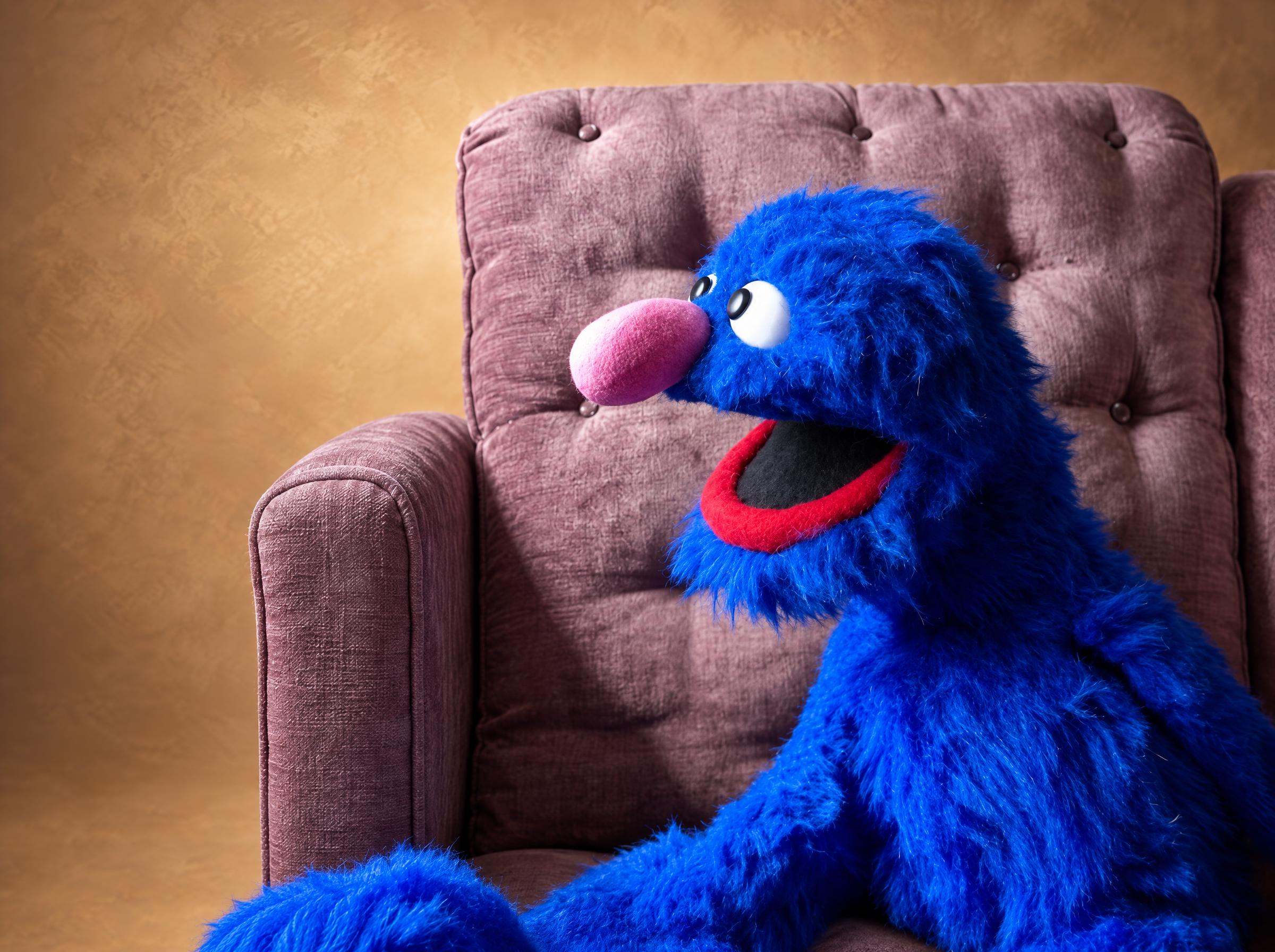 Handmade Grover plush sewn to order, bright blue fur, pink nose and red-lipped smile in a mauve armchair