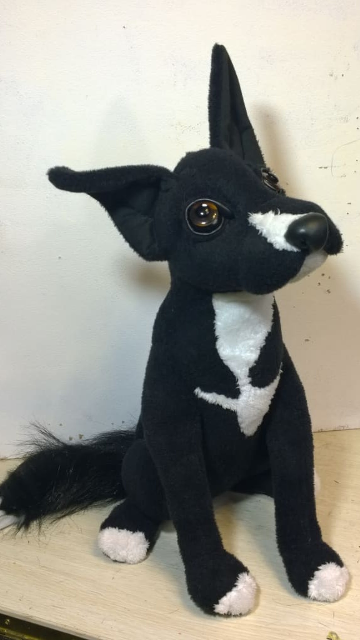 Lucky, a realistic plush dog made from a client's photos, sitting on a table with one ear up, handmade