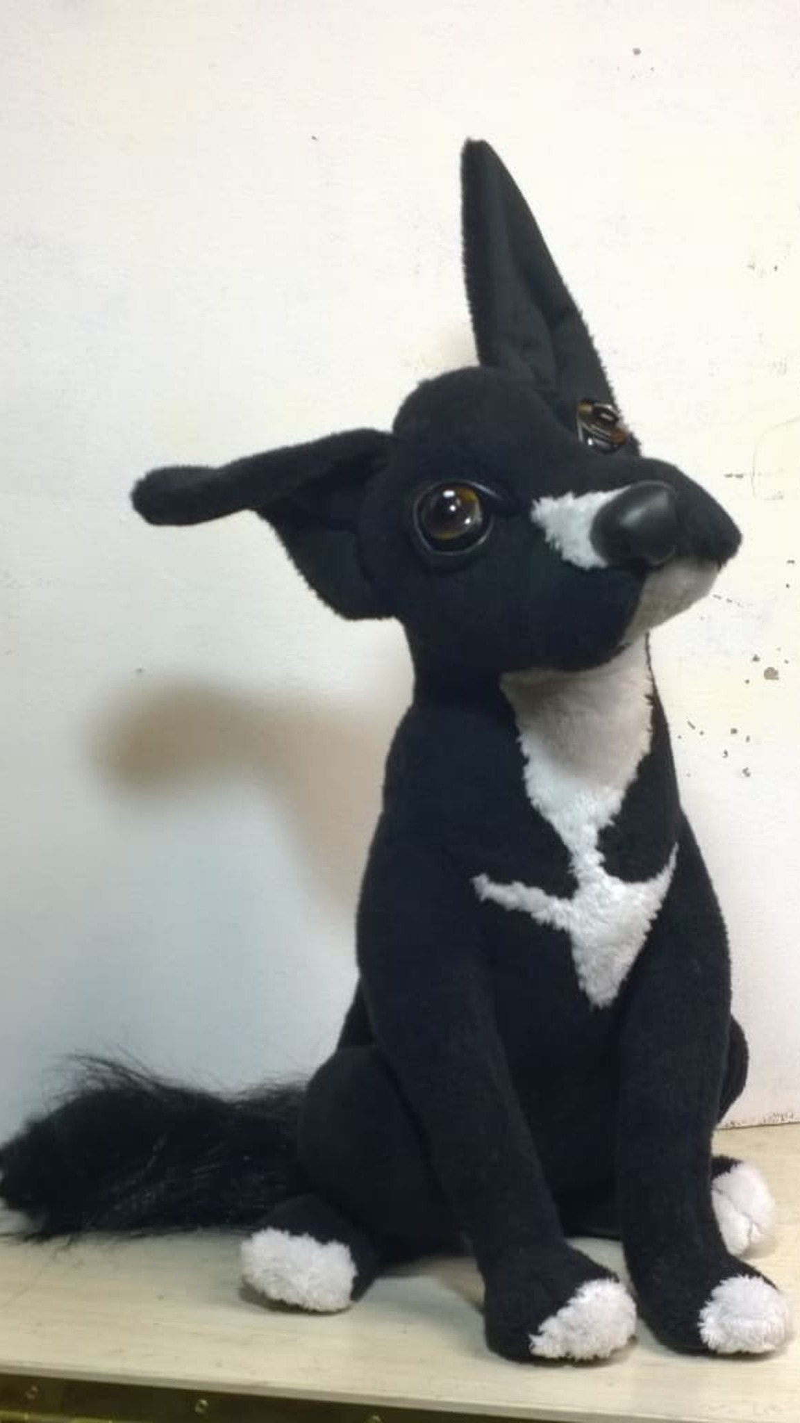 Black and white stuffed animal dog Lucky with a fluffy tail, a custom pet plush sewn by hand to order
