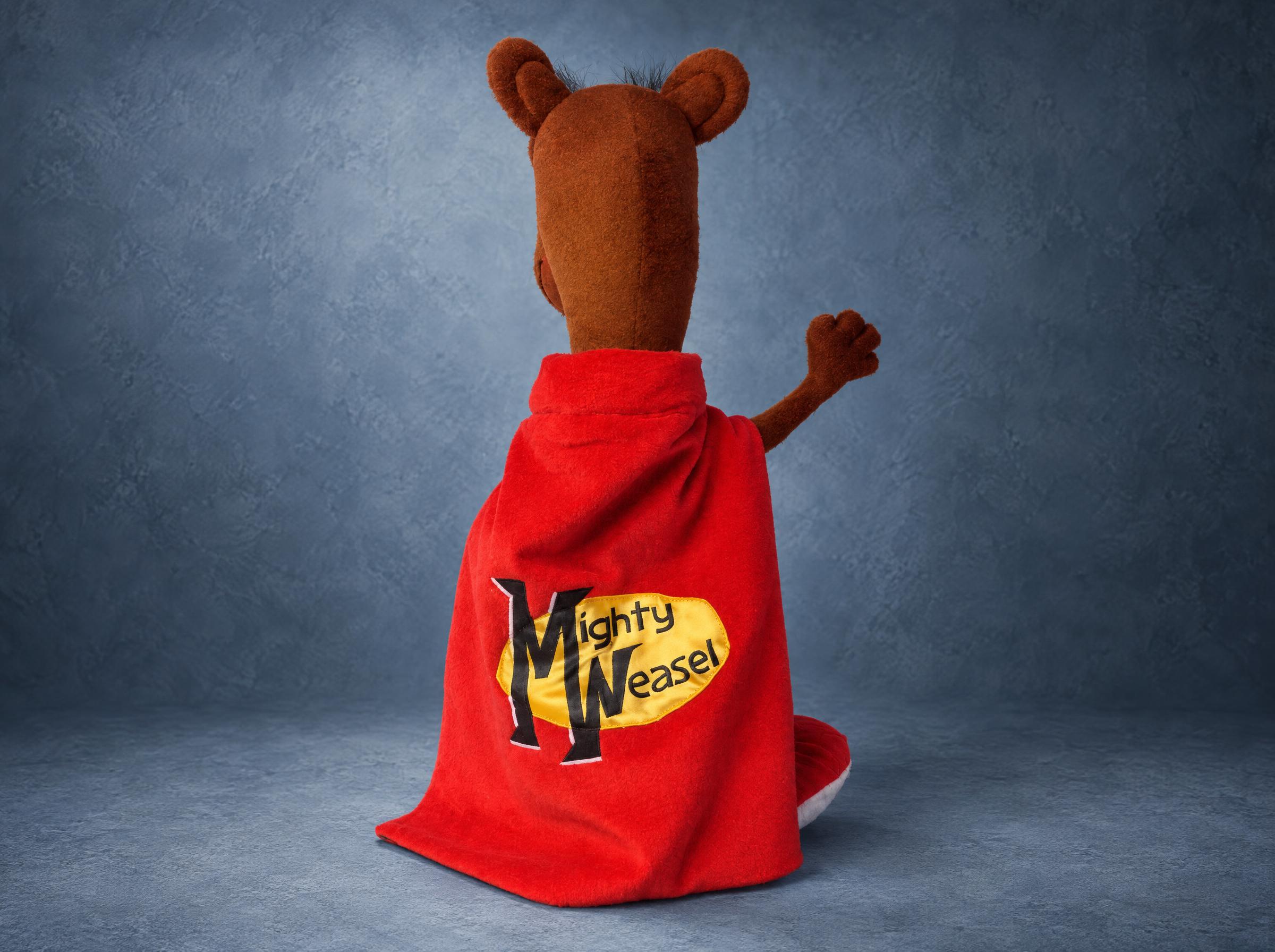 Back of the Mighty Weasel plush: a red cape with the name Mighty Weasel printed on it, a custom OC toy made to order