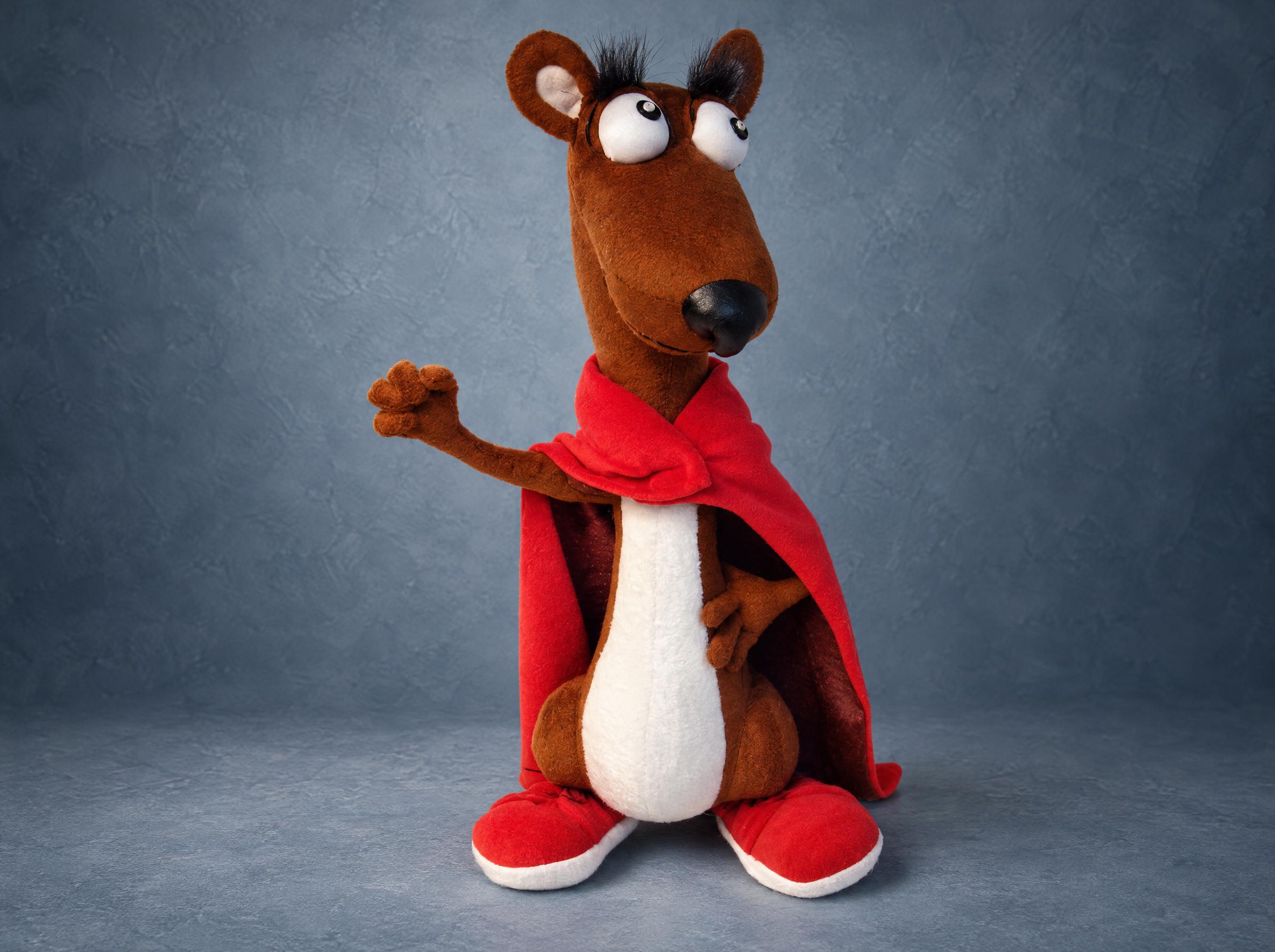 Mighty Weasel plush in a red cape and red shoes with a fist raised, a customer's own character sewn to order from his sketch