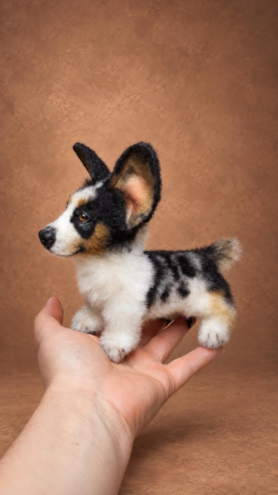 Small corgi stuffed animal on an open palm, a handmade replica of a customer's blue merle dog
