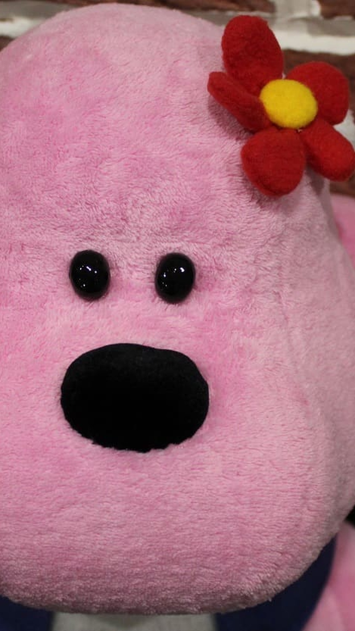Custom mascot plush Lucy the pink gorilla with bead eyes and a red flower, sewn by hand to order
