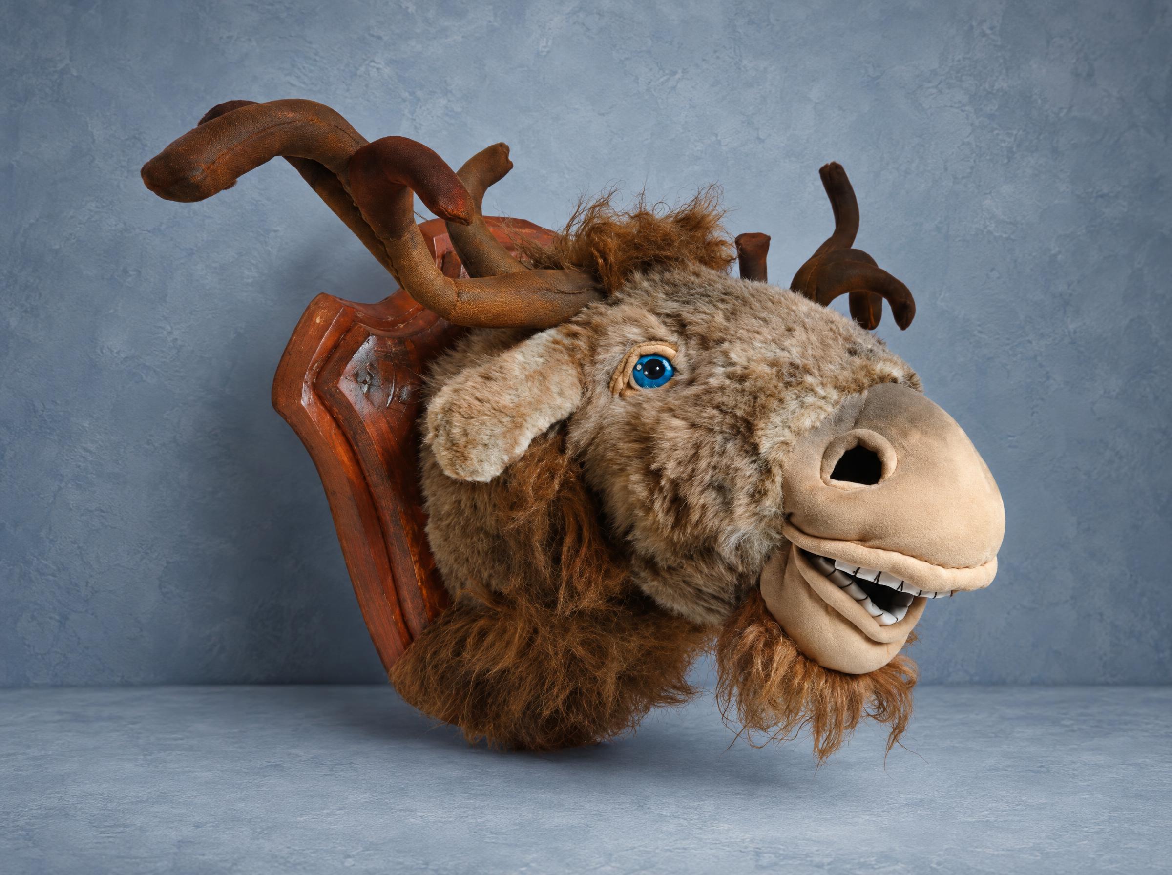 Plush moose head, faux taxidermy made to order: grinning, blue eyes, fabric antlers on a brown wall plaque