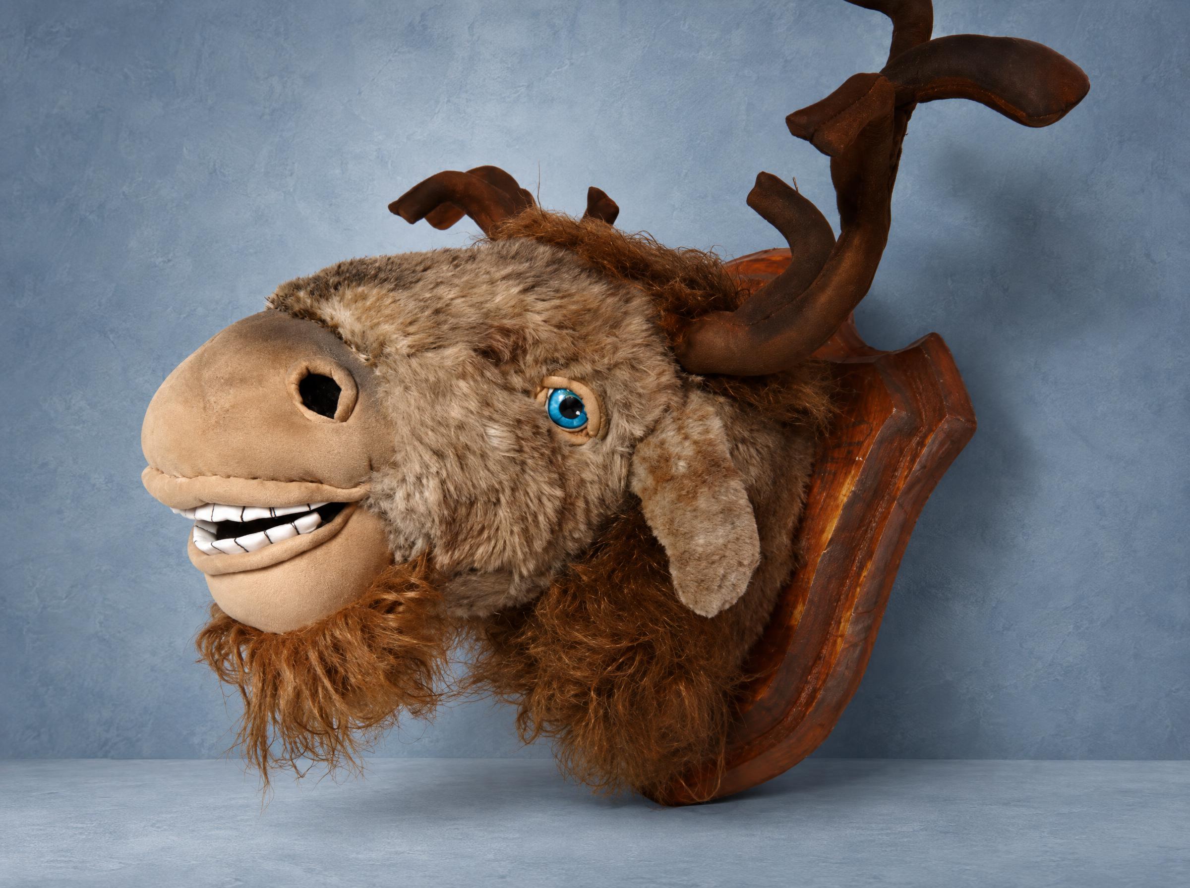Plush taxidermy moose trophy with blue eyes Plush taxidermy moose trophy facing left, bright blue eyes and faux fur beard, custom sewn for a cabin wall