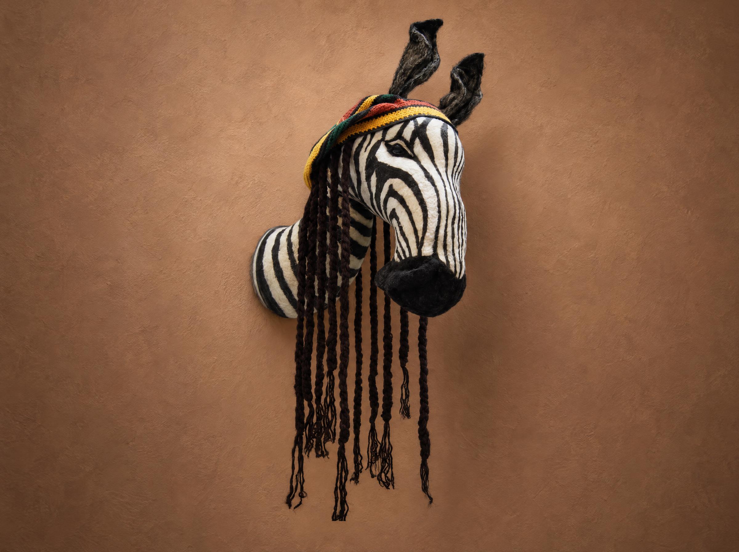 Plush zebra head wall mount, faux taxidermy made to order, with a red-yellow-green cap and yarn braids