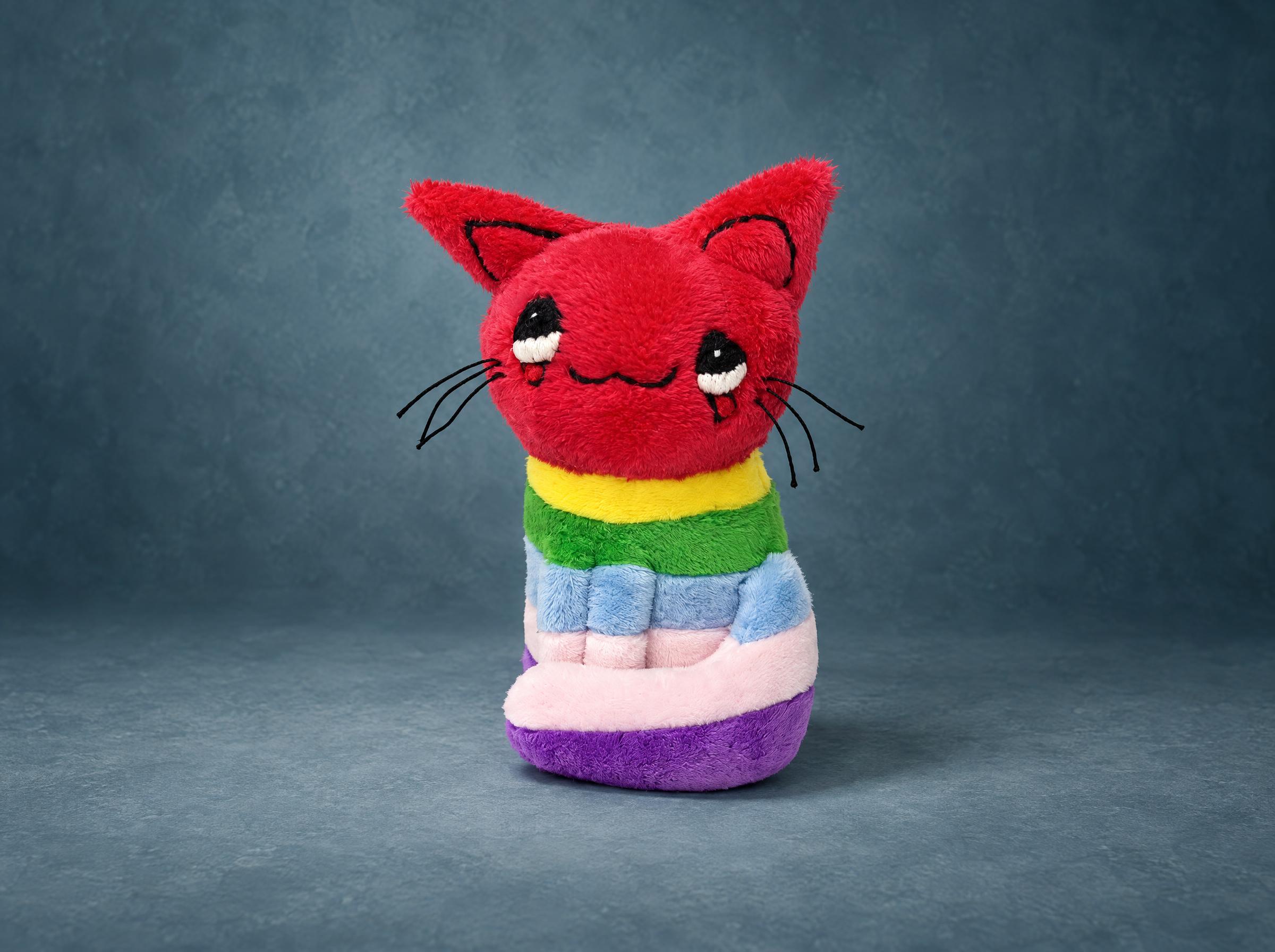 Rainbow cat plush made to order from a child's drawing: red head, teary embroidered eyes, rainbow-striped body