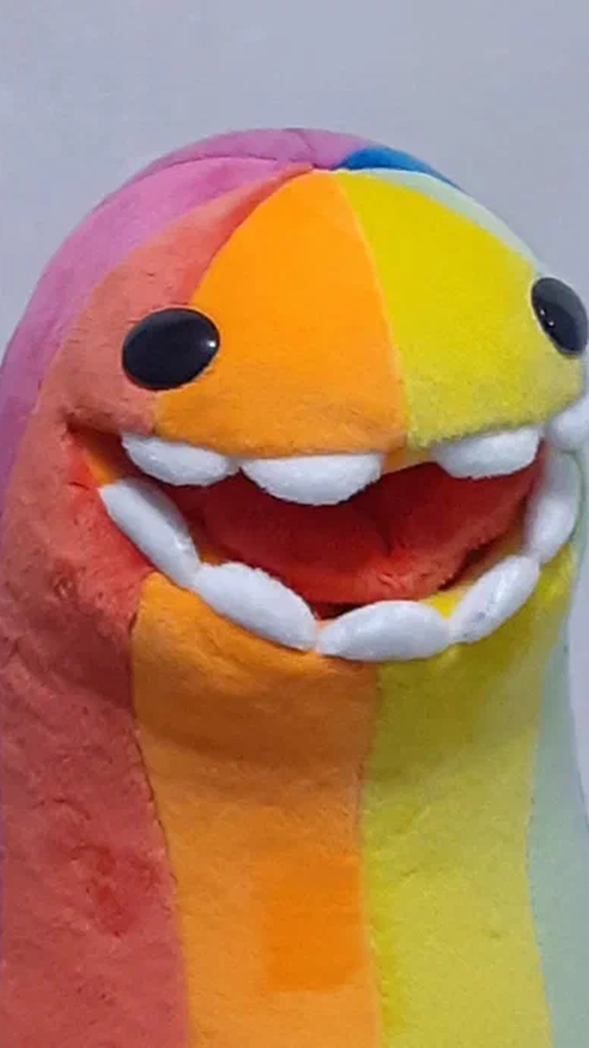 Rainbow monster plush face: shiny black eyes, red mouth and a row of soft white teeth, handmade to order