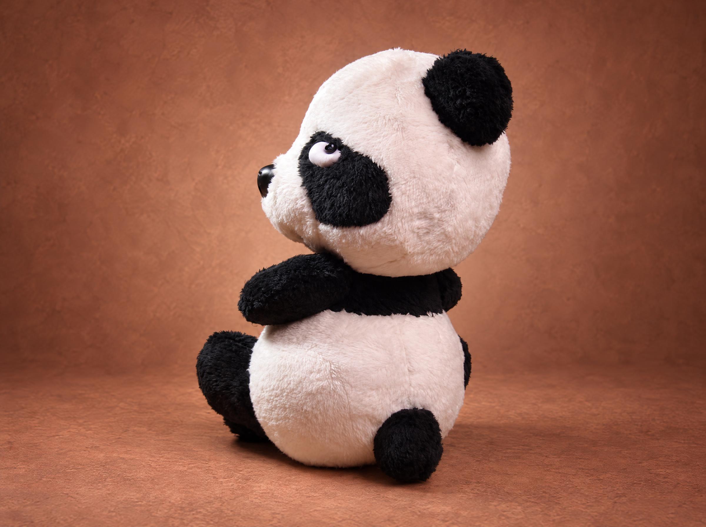 Resentful panda plush looking away with half-closed eyes and crossed arms, a mood sticker sewn to order