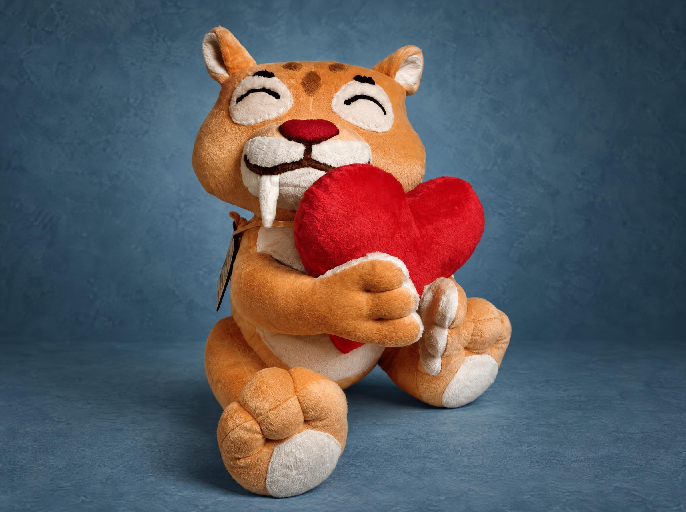 Custom sabre-toothed cat plush sewn to order from a chat sticker, hugging a big red heart