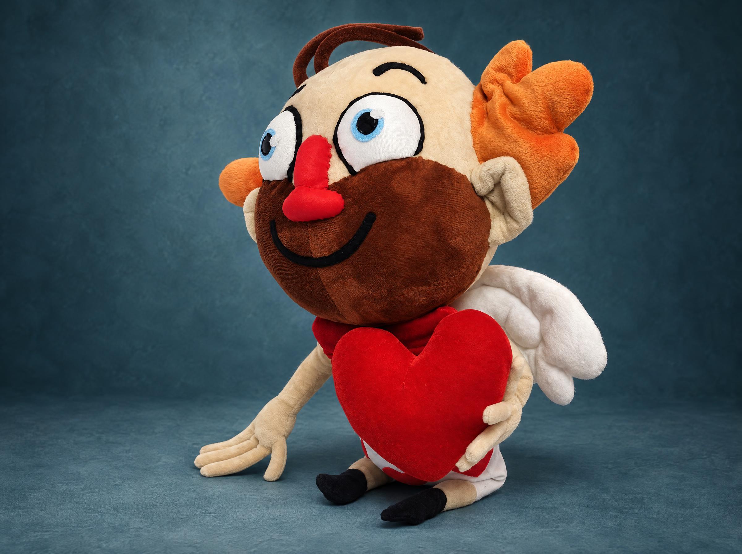 Sticker Plush Cupid With Wings and a Velvet Heart Sticker plush cupid with a round stubbly face, white wings and a red velvet heart in both hands, made to order