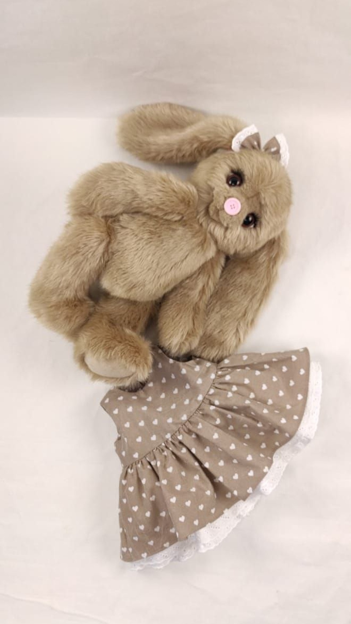 Teddy-style bunny plush sample lying beside its heart-print dress, soft fawn faux fur, sewn to order
