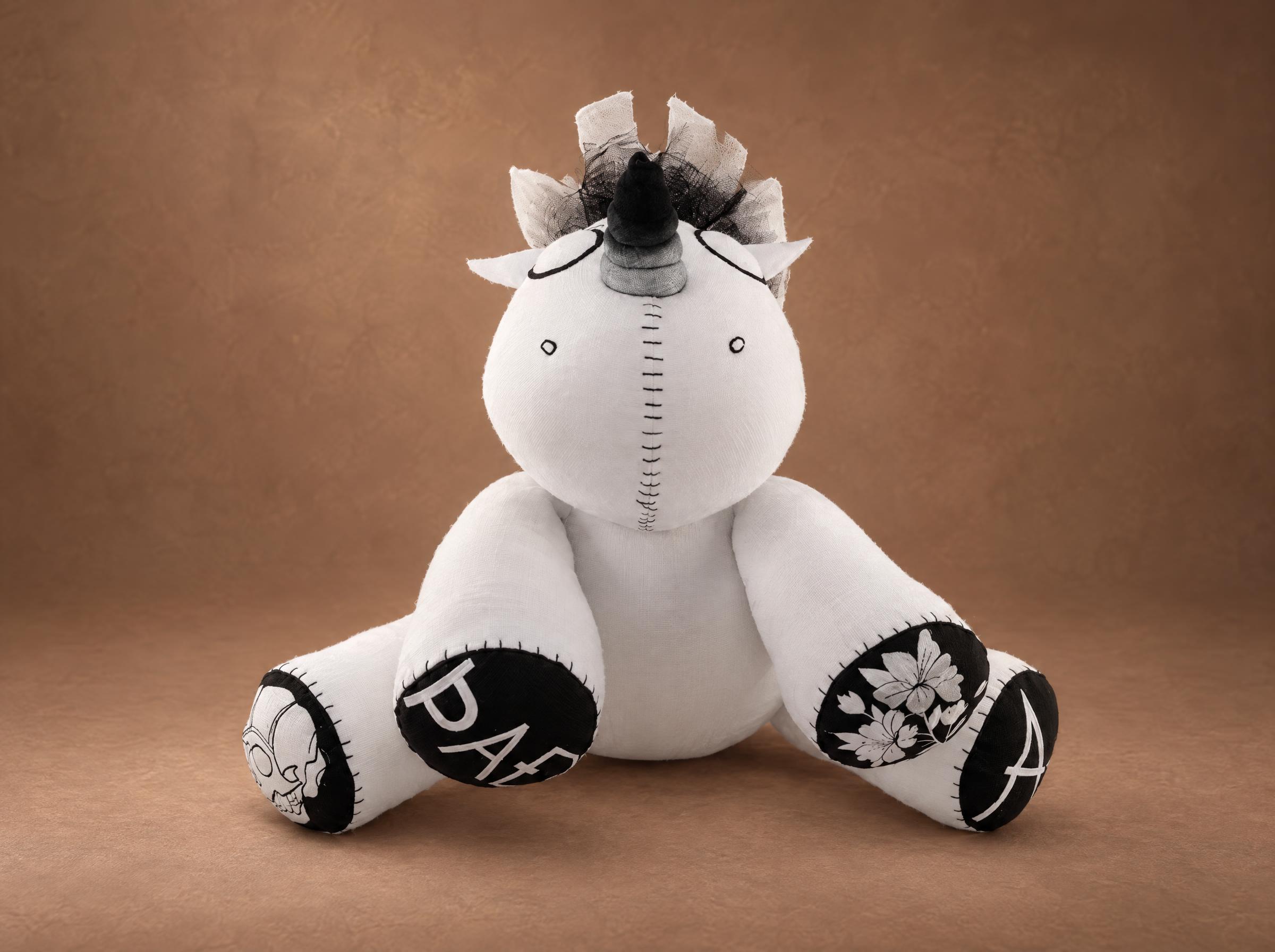 Handmade voodoo unicorn plush with hoof pads printed with a skull, flowers and letters, custom made to order