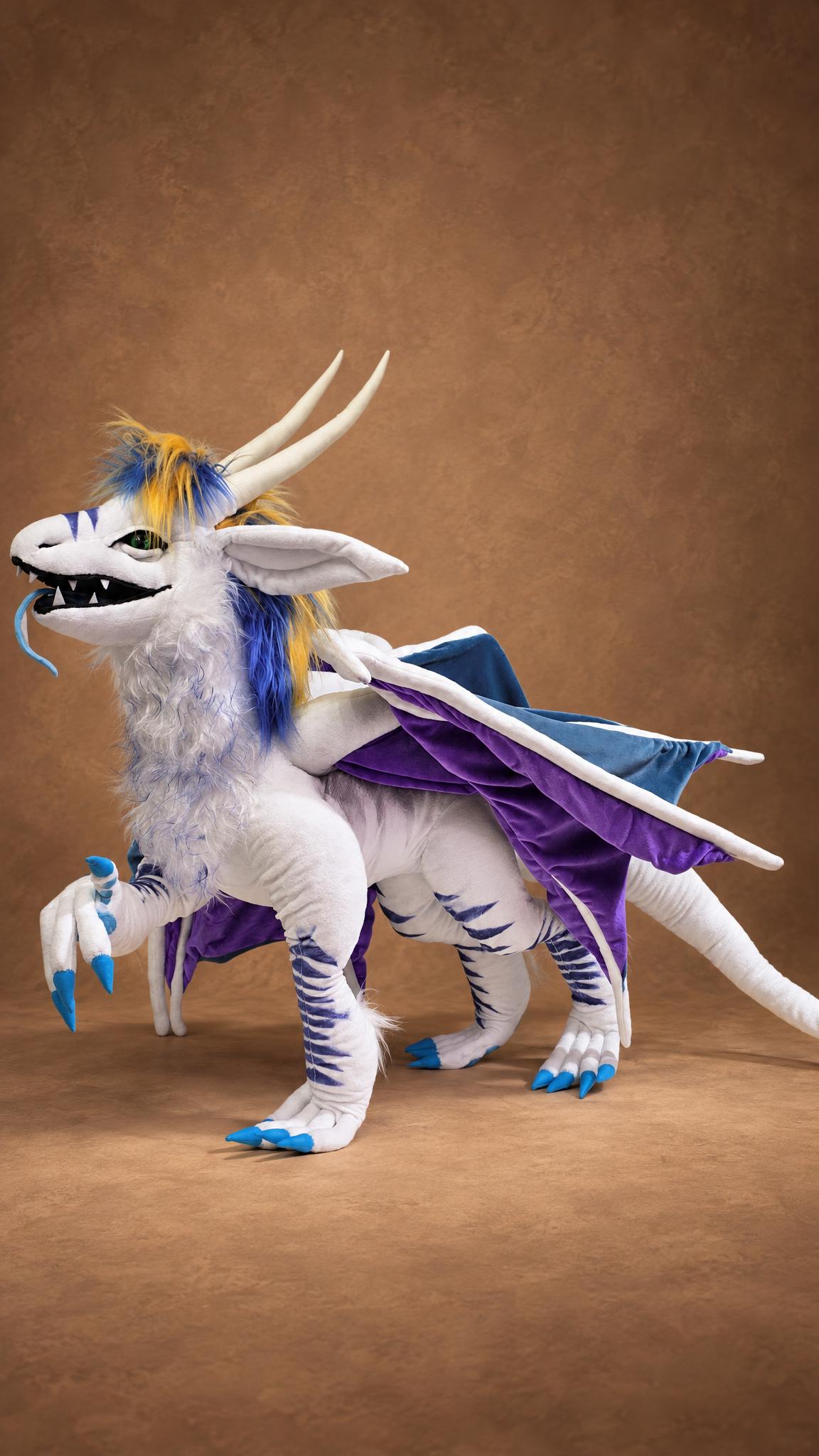 Handmade ice dragon plush with a raised front paw, green eyes and long cream horns, a custom dragon OC