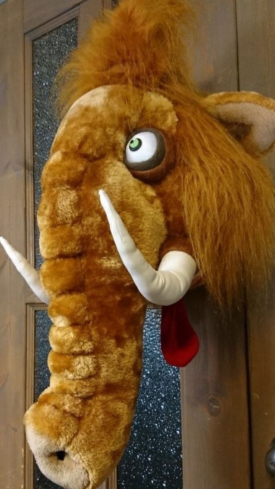 Custom woolly mammoth head wall mount in plush, handmade to order, hanging on a wooden door, googly eye