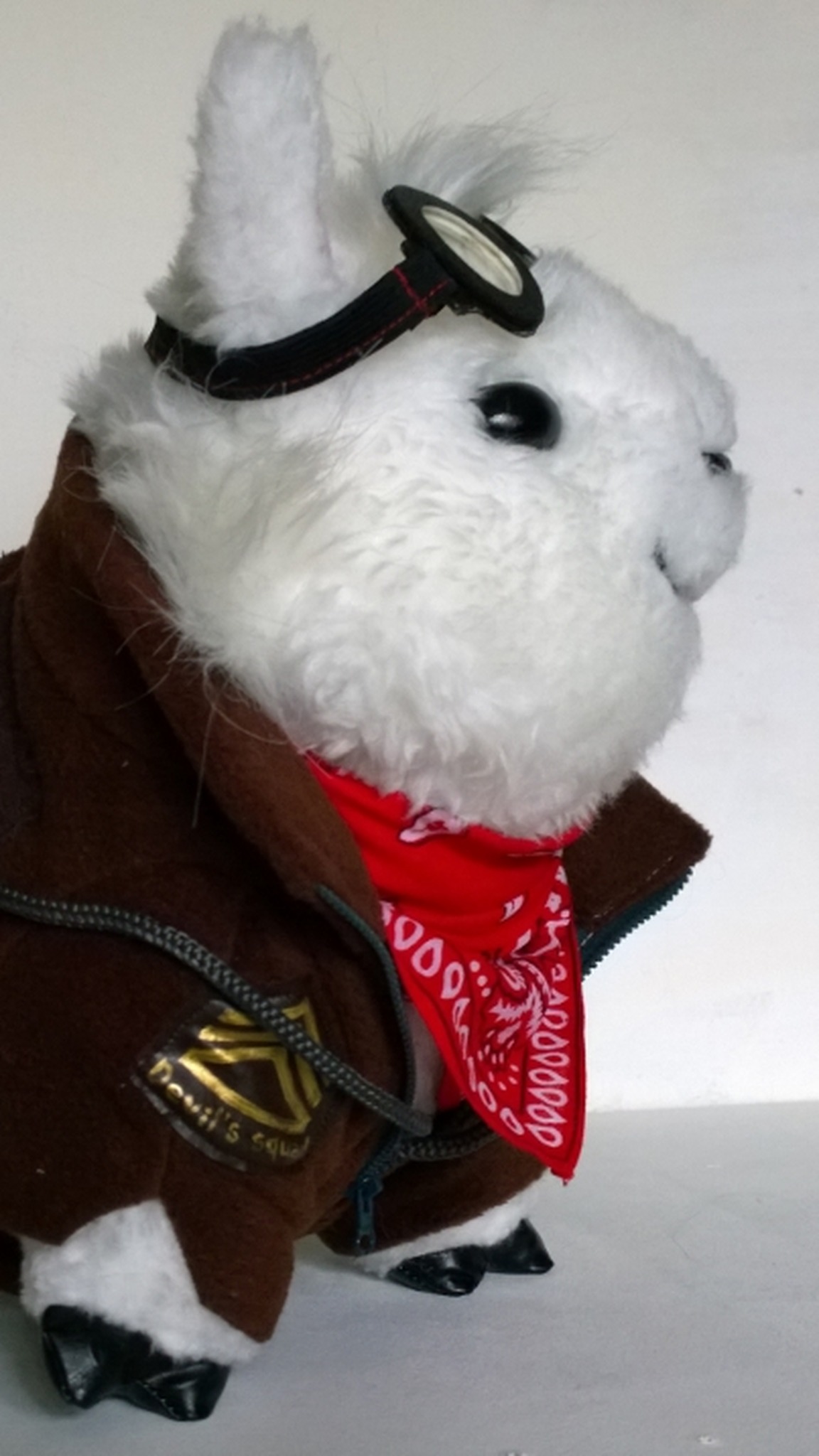 Alpaca stuffed animal made to order, in a brown aviator jacket with a patch, goggles and a red bandana
