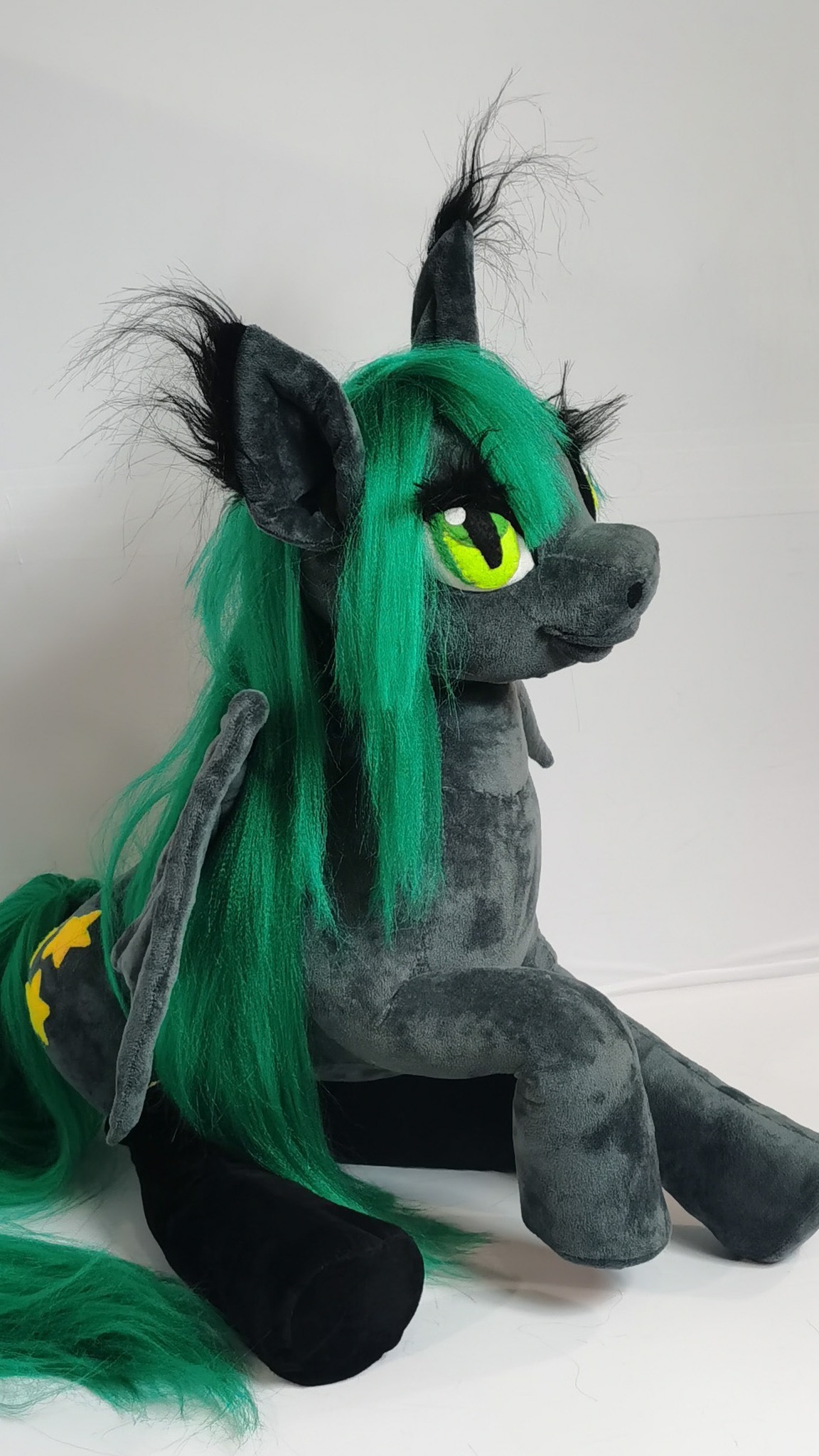 Sitting bat pony plush with black ear tufts, green eyes and a long green tail, made to order for one fan