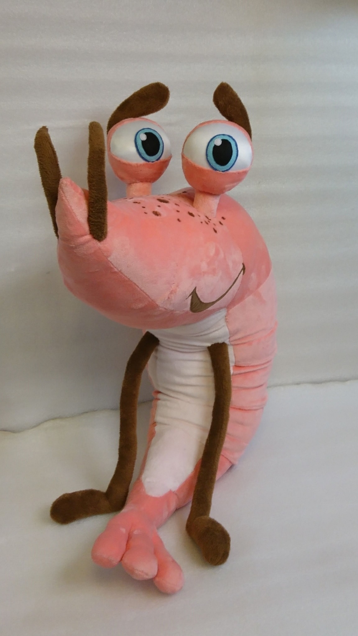 Big shrimp plush toy sitting up on its ribbed pink tail, a cartoon company mascot handmade from a drawing