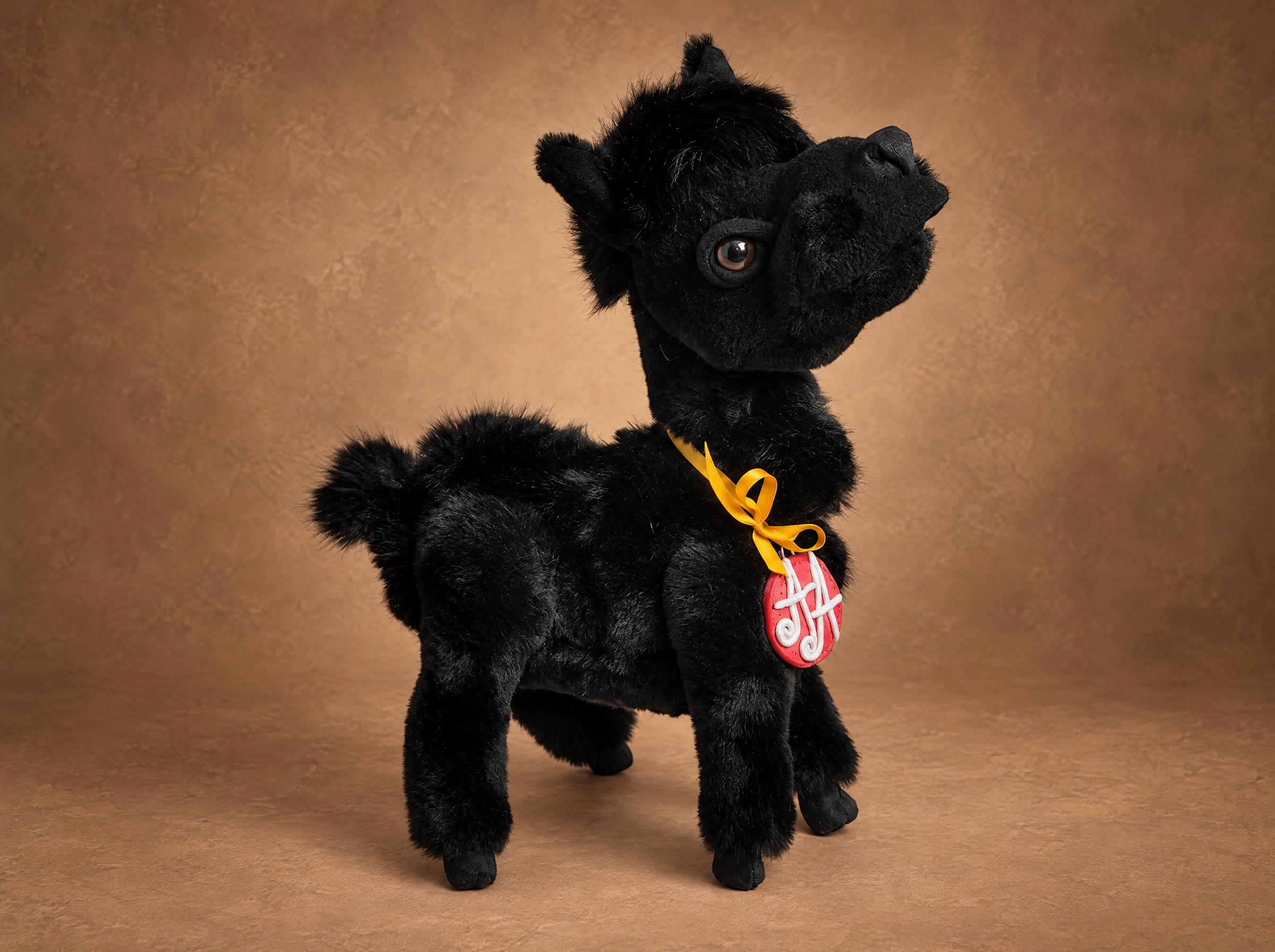 Black llama plush in faux fur with a yellow ribbon and red monogram tag, handmade to order from a photo