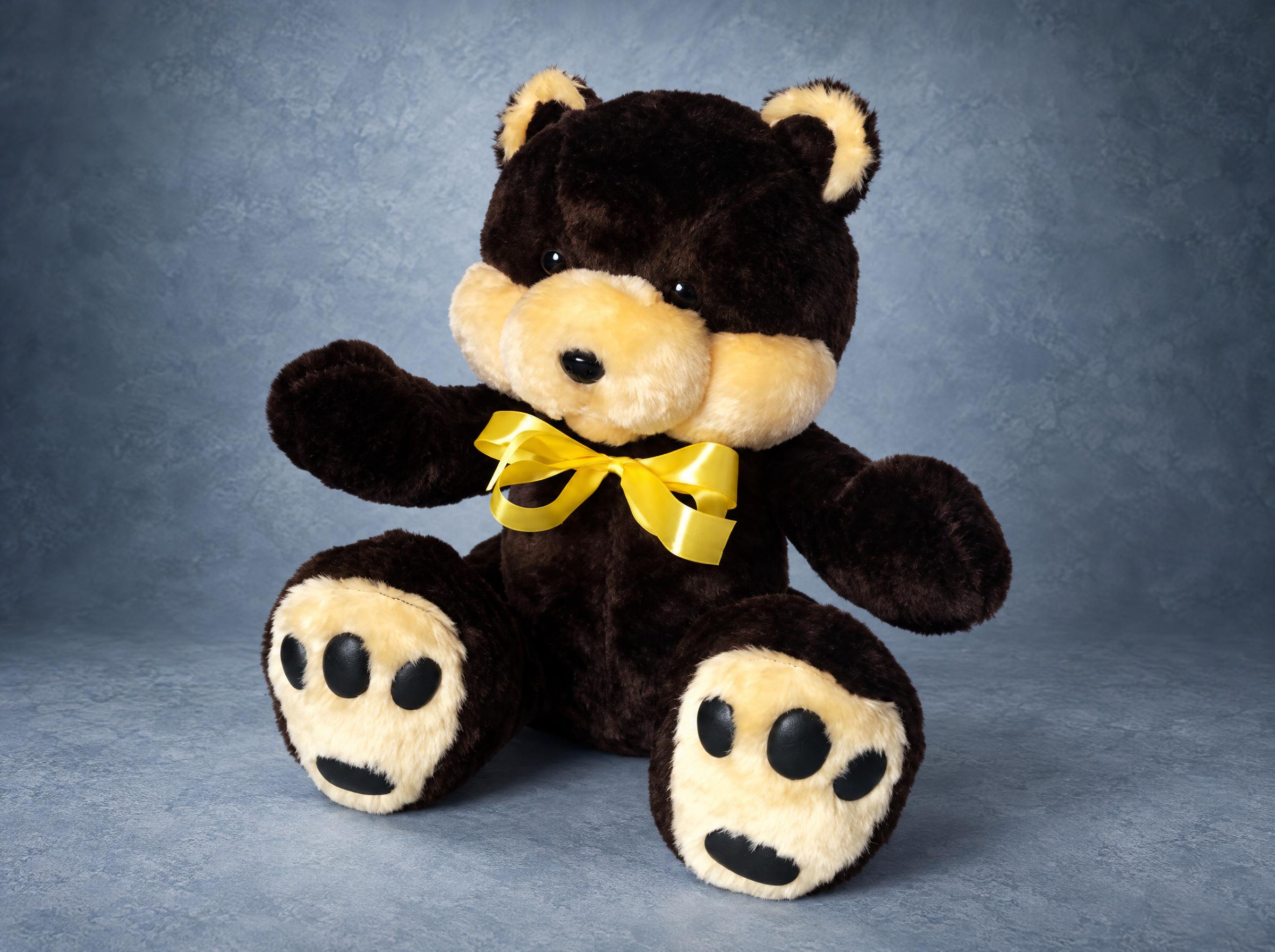 Black teddy bear plush with cream cheeks, cream paw pads and a yellow satin bow, handmade to order