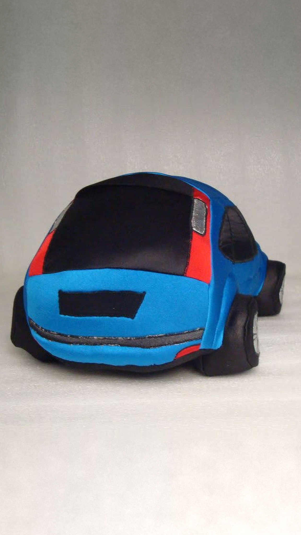 Soft blue car plush hatch with red fabric panels, silver taillights and a black bumper, sewn to order