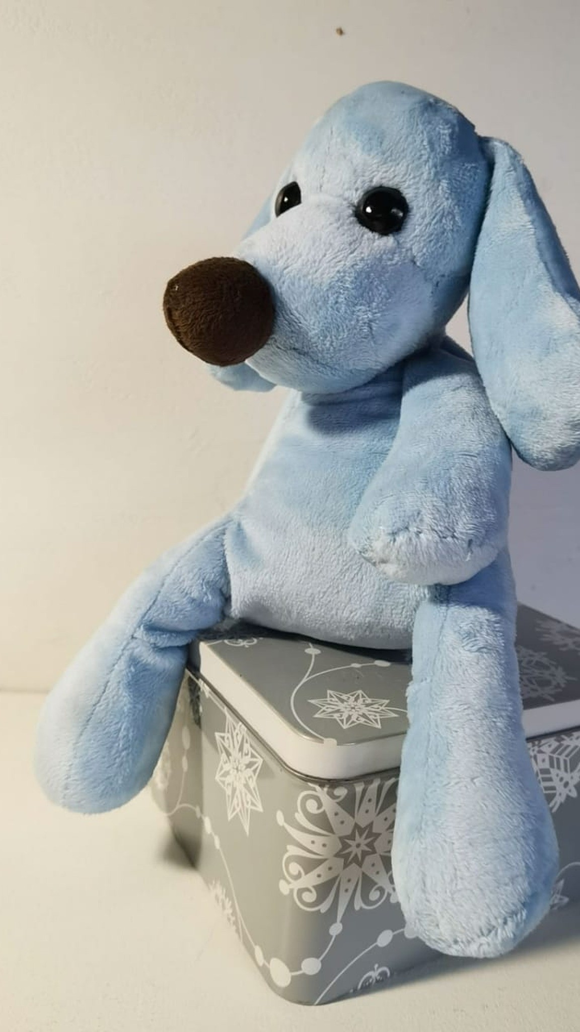 Light blue dog plush with long loose legs dangling over a tin box, sewn by hand to order