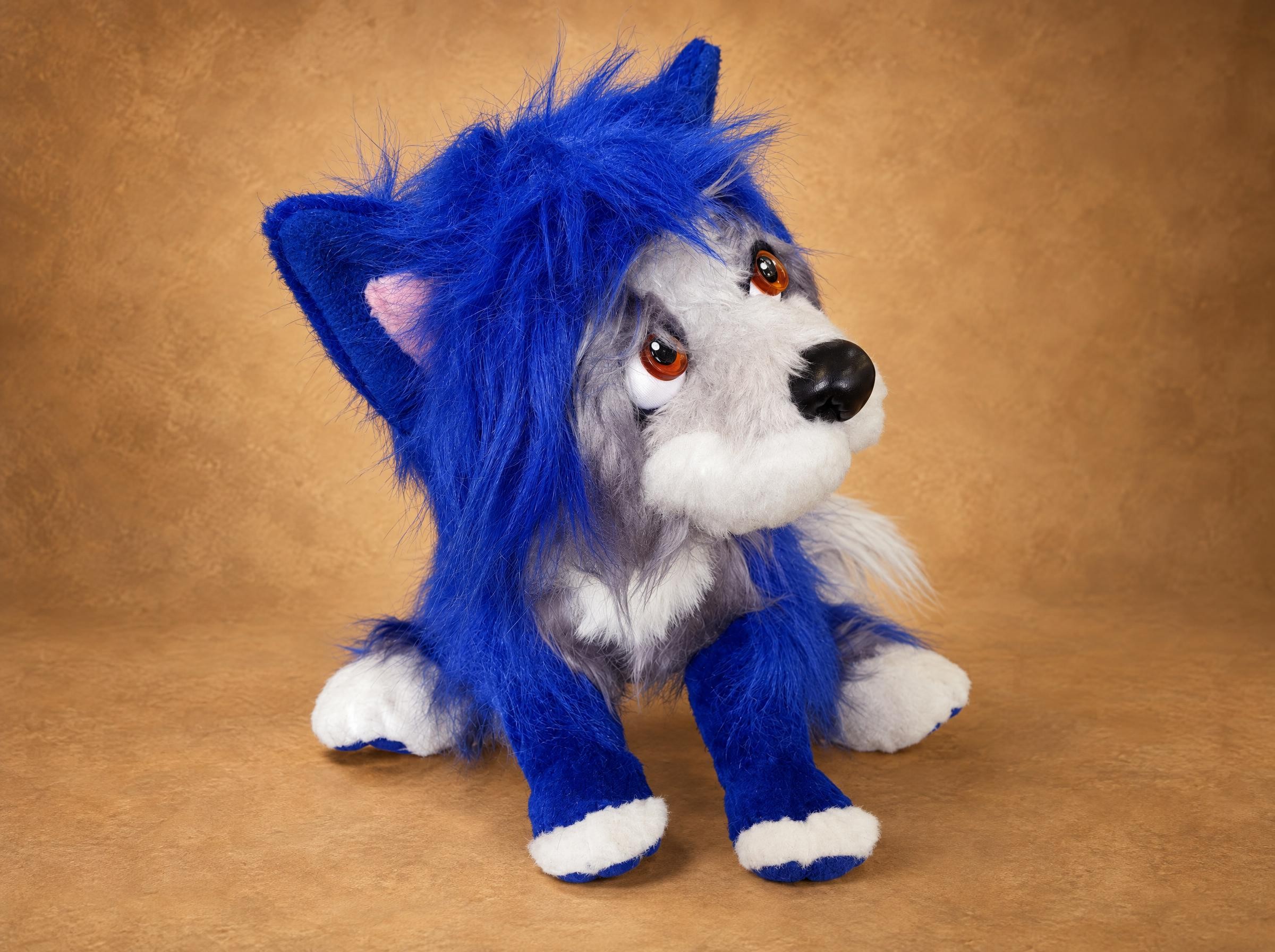 Blue dog plush sewn to order in shaggy royal-blue faux fur, amber eyes under a messy fringe, white paw tips