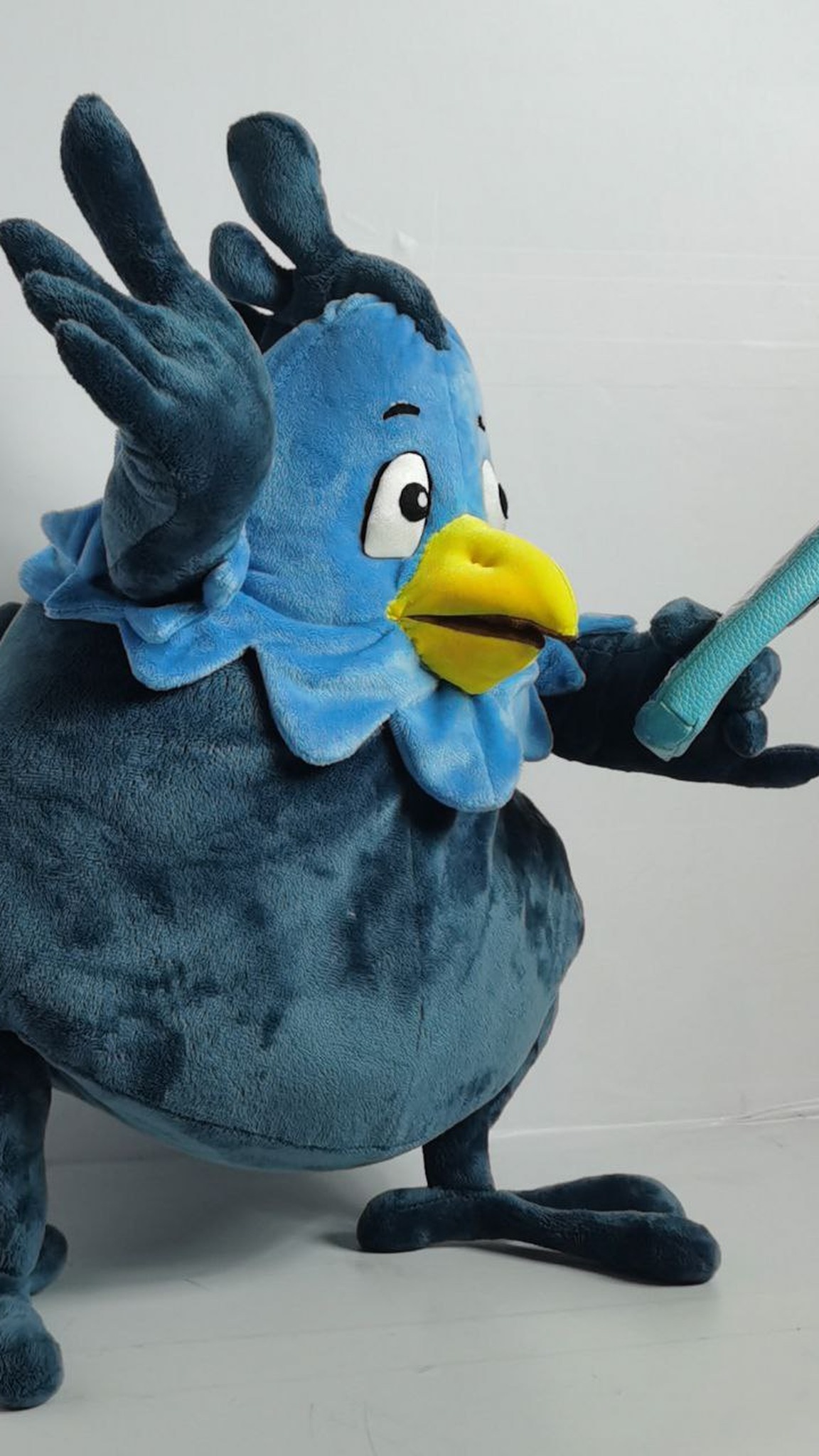 Blue phoenix plush waving a feathered wing, embroidered eyes and yellow beak, custom mascot sewn to order