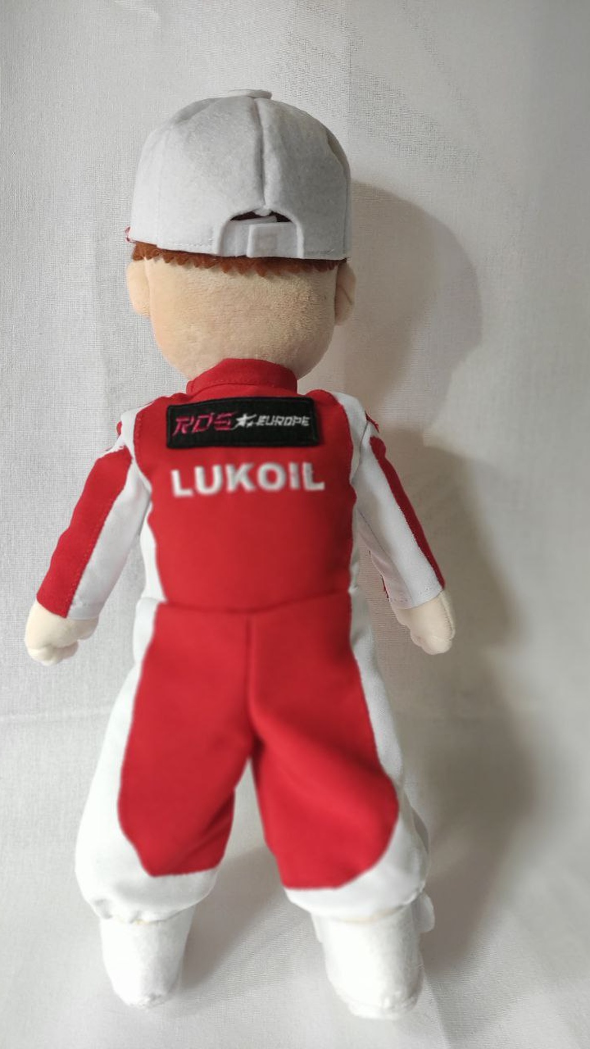 Back of the branded plush doll: logo and sponsor patch on the racing suit, cap turned backwards, made to order