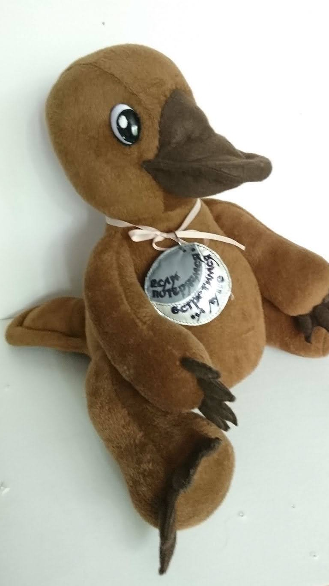 Brown platypus plush with a flat tail, clawed webbed feet and a medal saying meet on the Moon, made to order