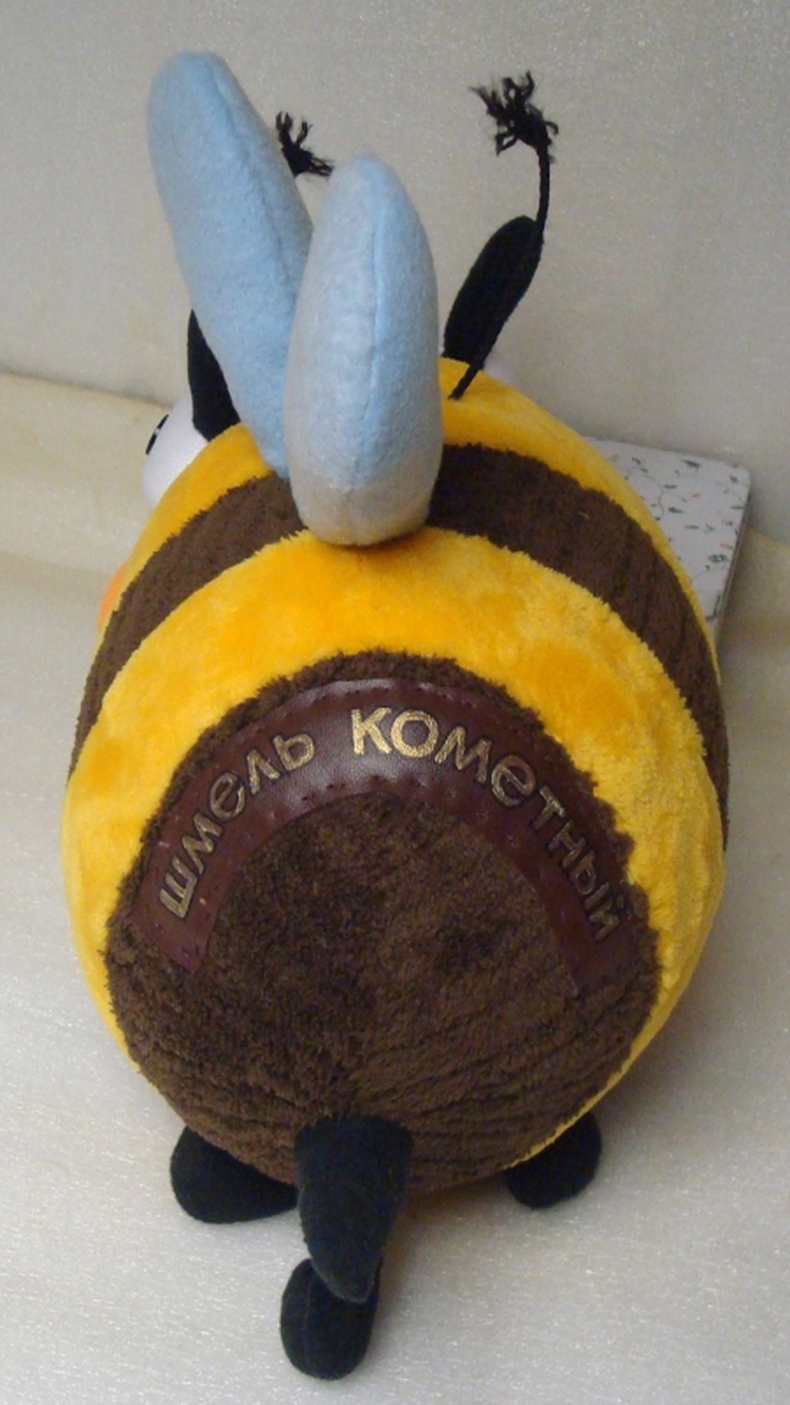 Brown name patch with gold letters reading comet bumblebee in Russian on the back of a custom bumblebee plush